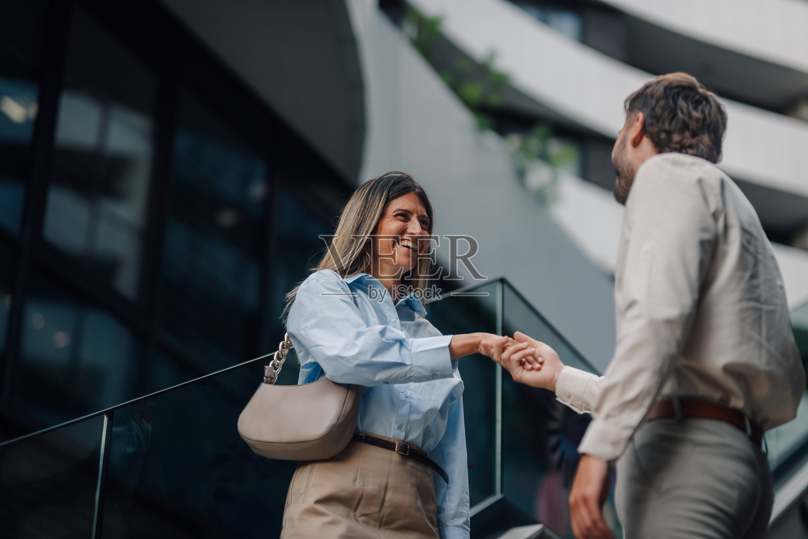 商务人士在现代建筑前的楼梯上握手照片摄影图片