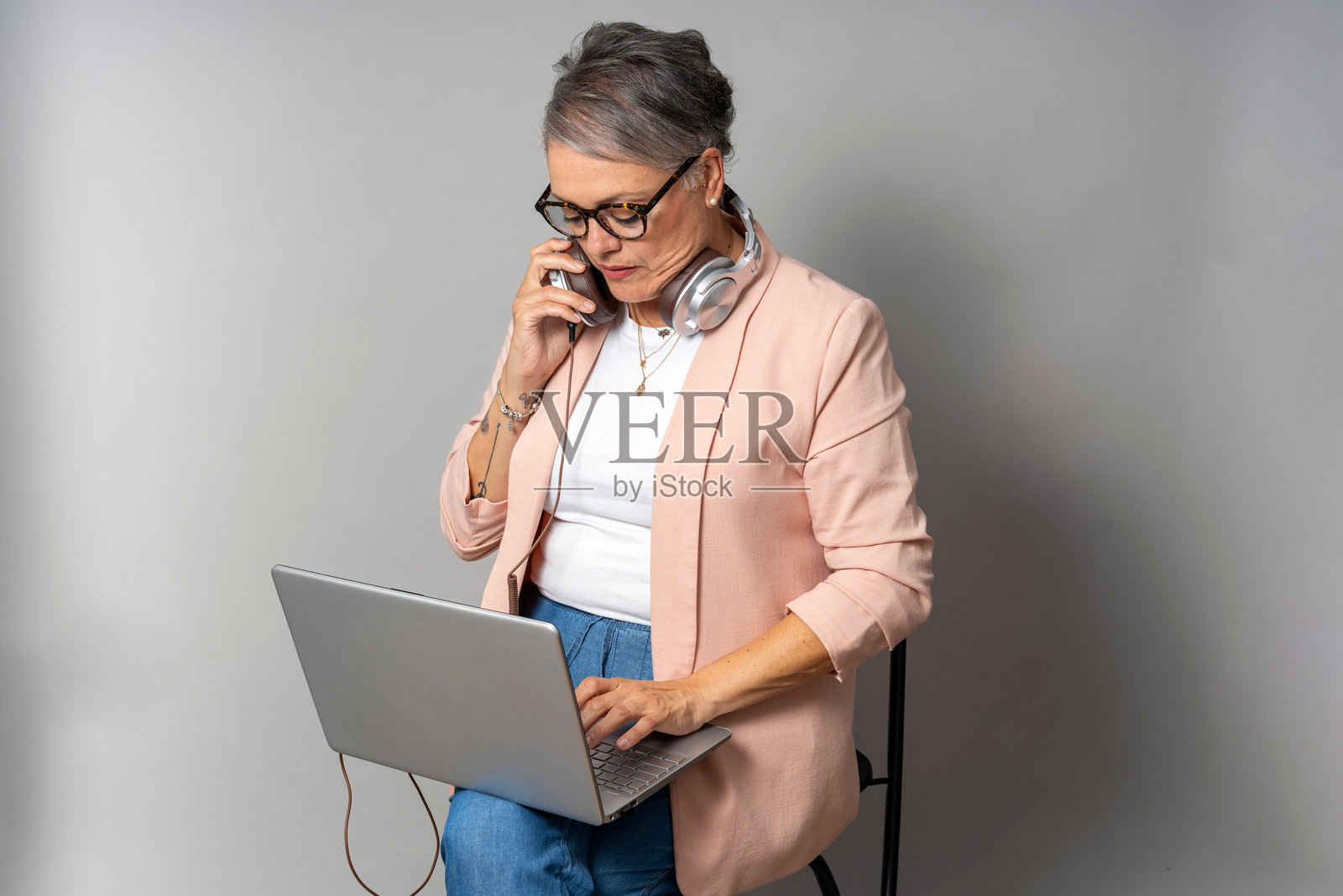 高级女商人一边使用笔记本电脑一边打电话。照片摄影图片