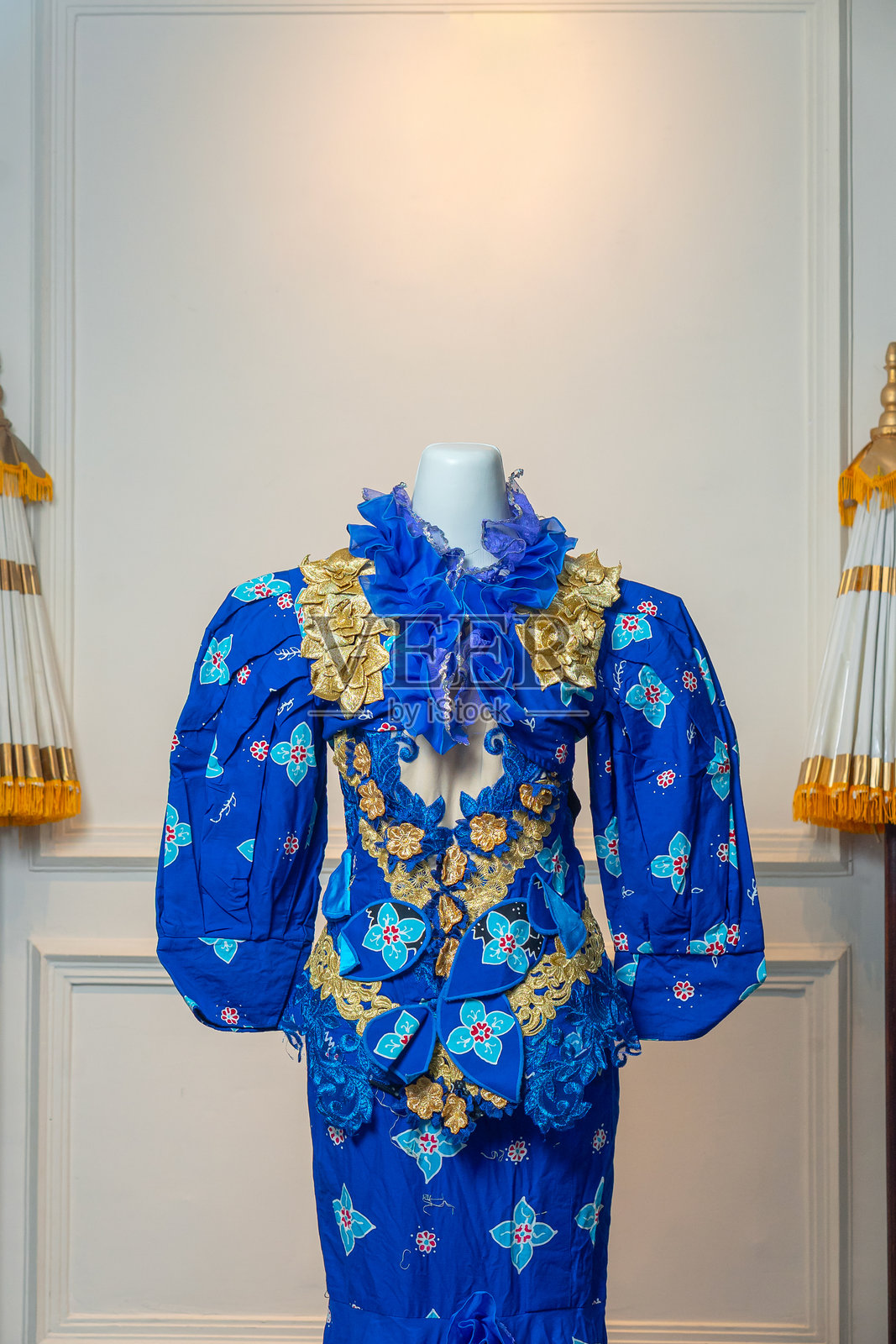 一件引人注目的皇家蓝色礼服，配有泡袖、金色花卉刺绣和大胆的刺绣图案，展示在模特上，展现出优雅、文化遗产和精湛的工艺。照片摄影图片
