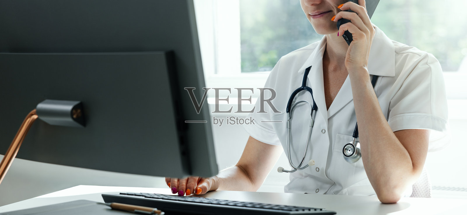 医疗咨询，医院服务台。医生在诊所办公室使用电脑并打电话。留白空间。照片摄影图片