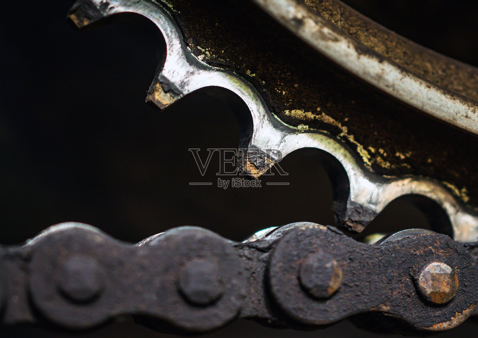 摩托车链条连接在后齿轮上，特写镜头显示脏污的二手摩托车链条。生锈的摩托车链条需要清洗和润滑。照片摄影图片