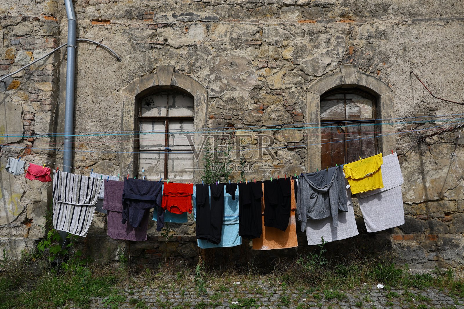 在波兰克沃兹科，一座古老的石头建筑前，五彩斑斓的衣物挂在晾衣绳上。照片摄影图片