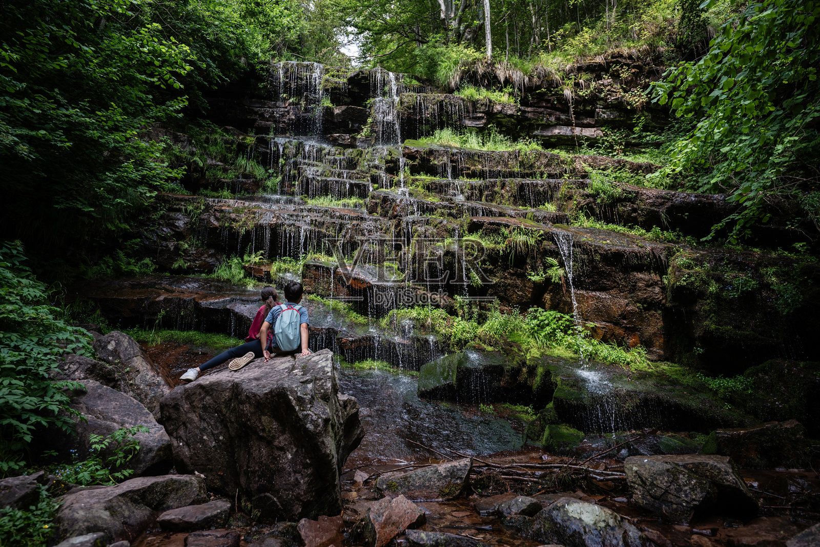徒步旅行者在郁郁葱葱的森林中靠近瀑布休息照片摄影图片