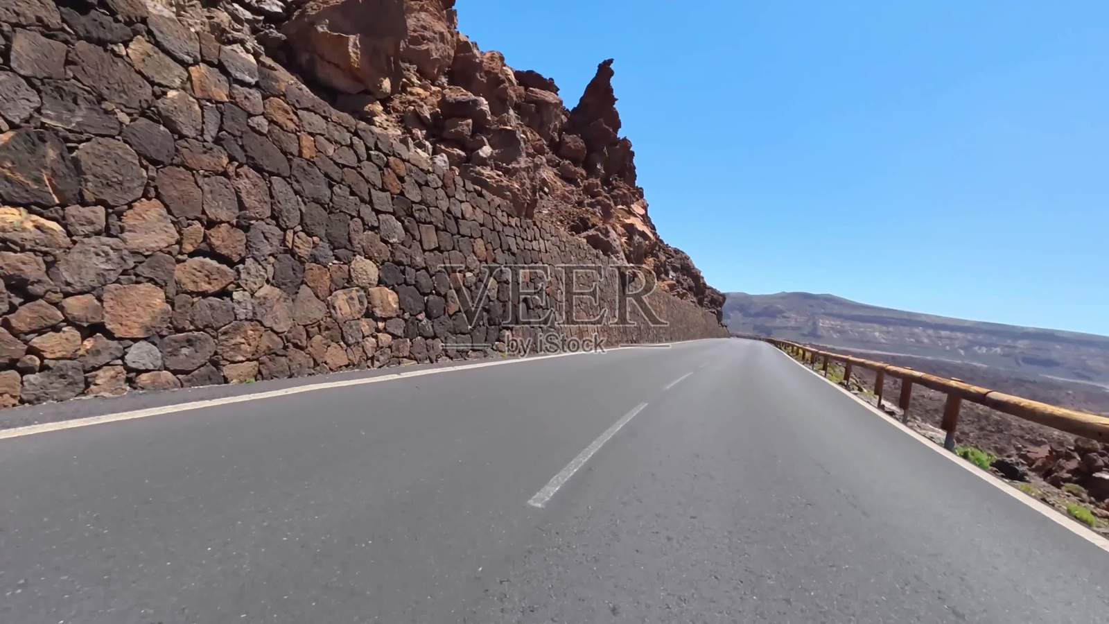 一条美丽的山路蜿蜒穿过雄伟的岩石悬崖，蓝天清澈如洗。照片摄影图片