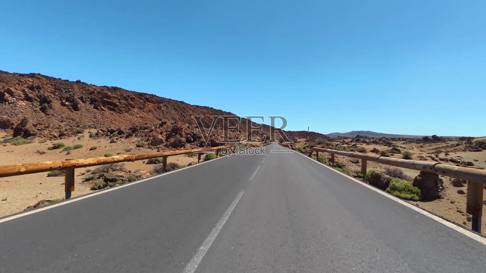 一条美丽的风景道路蜿蜒穿过岩石景观，蓝天清澈。照片摄影图片