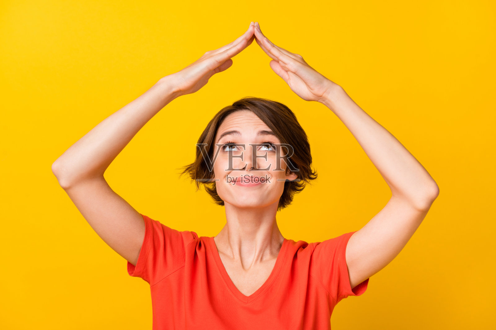 可爱的满意的人抬头看着，双臂张开，做出家居姿势，背景为黄色。照片摄影图片