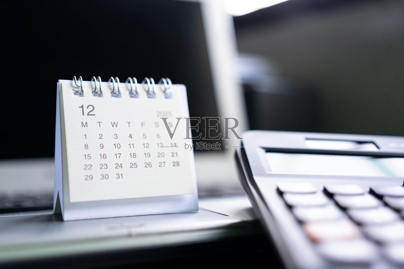 带计算器和笔记本电脑的桌面日历，适用于2025年12月的商业规划。适合与商业规划、财务、会计、截止日期和日程安排相关的概念。照片摄影图片
