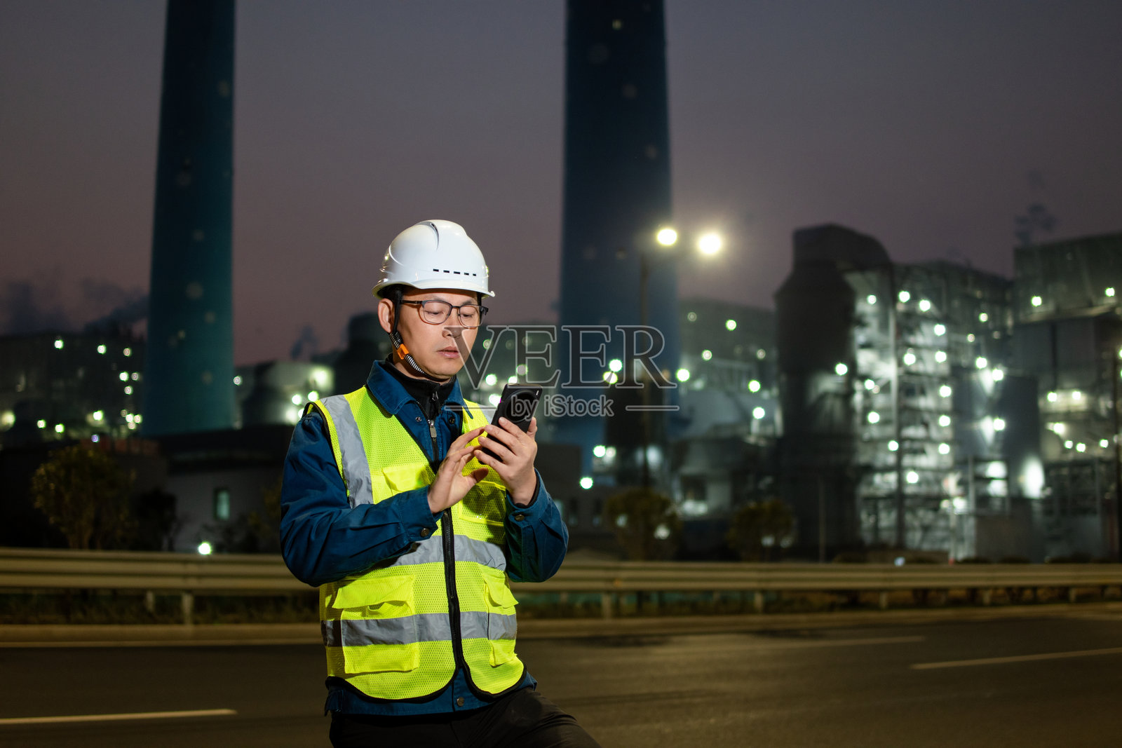 中年男性工程师在火力发电厂使用智能手机照片摄影图片
