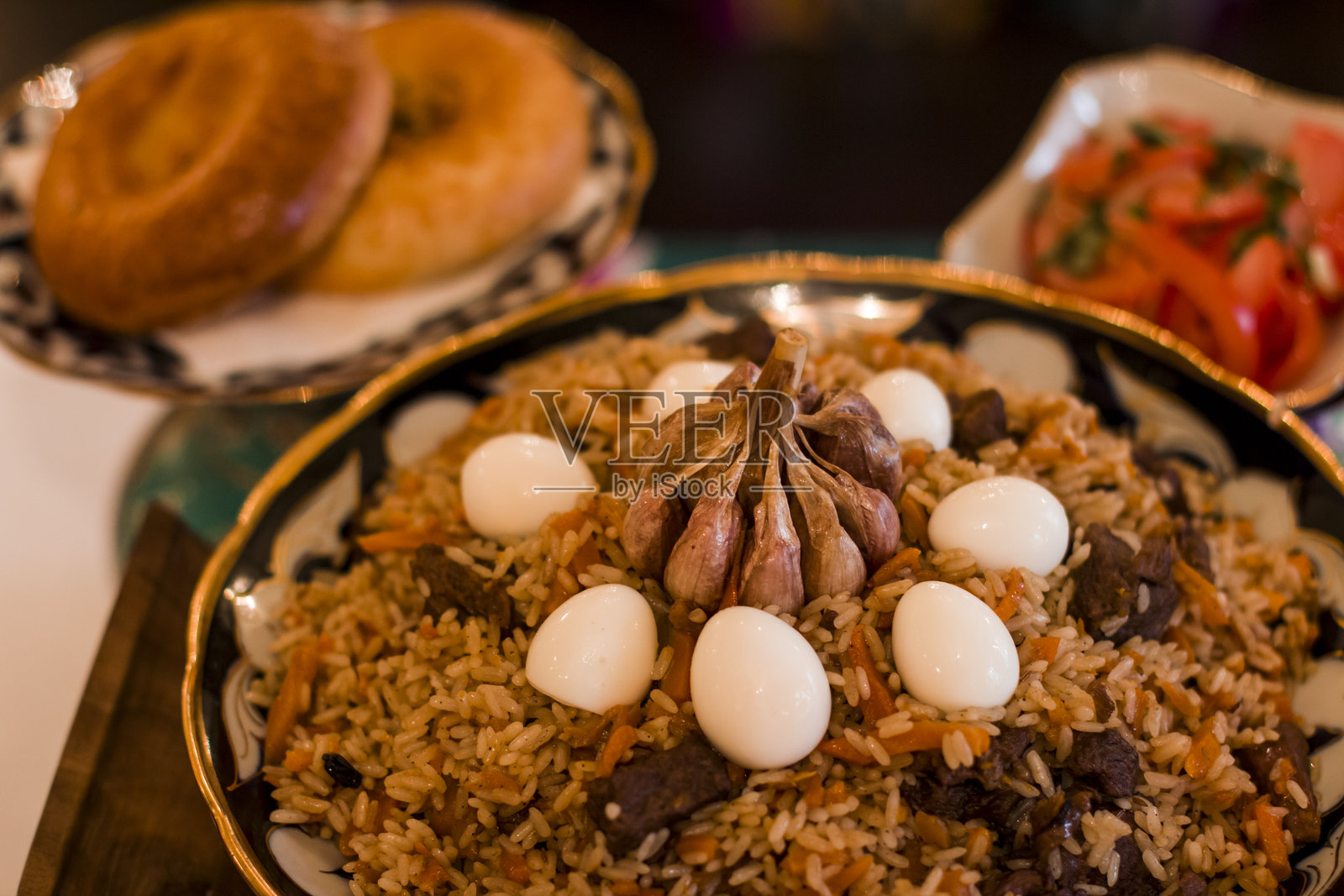 传统乌兹别克米饭菜肴，配有嫩肉、芳香香料，装饰以鸡蛋，旁边配有新鲜面包和沙拉，展示了文化美食。留白，菜单。照片摄影图片