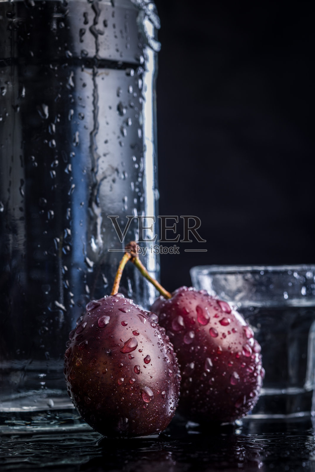 黑色桌子上的李子和蒸馏酒。李子白兰地酒。照片摄影图片