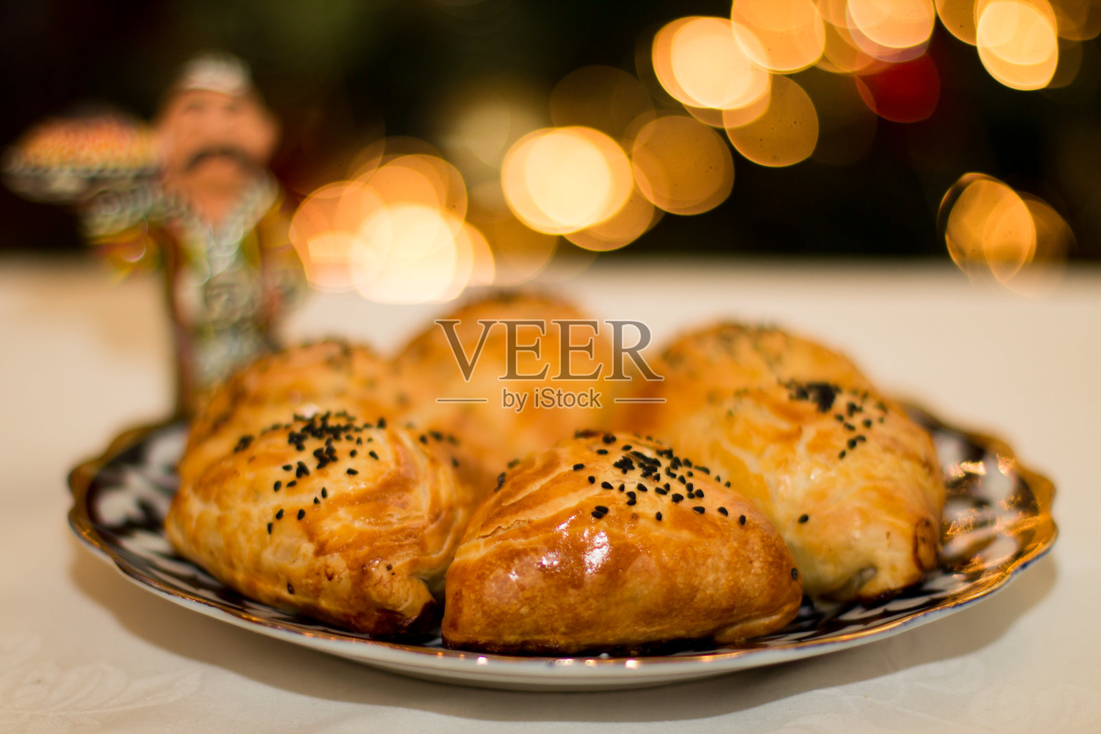 乌兹别克的萨姆萨点心精美地摆放在装饰盘上，展现出金黄色的外皮和黑芝麻，完美适合美食爱好者和文化探索。留白，菜单。照片摄影图片