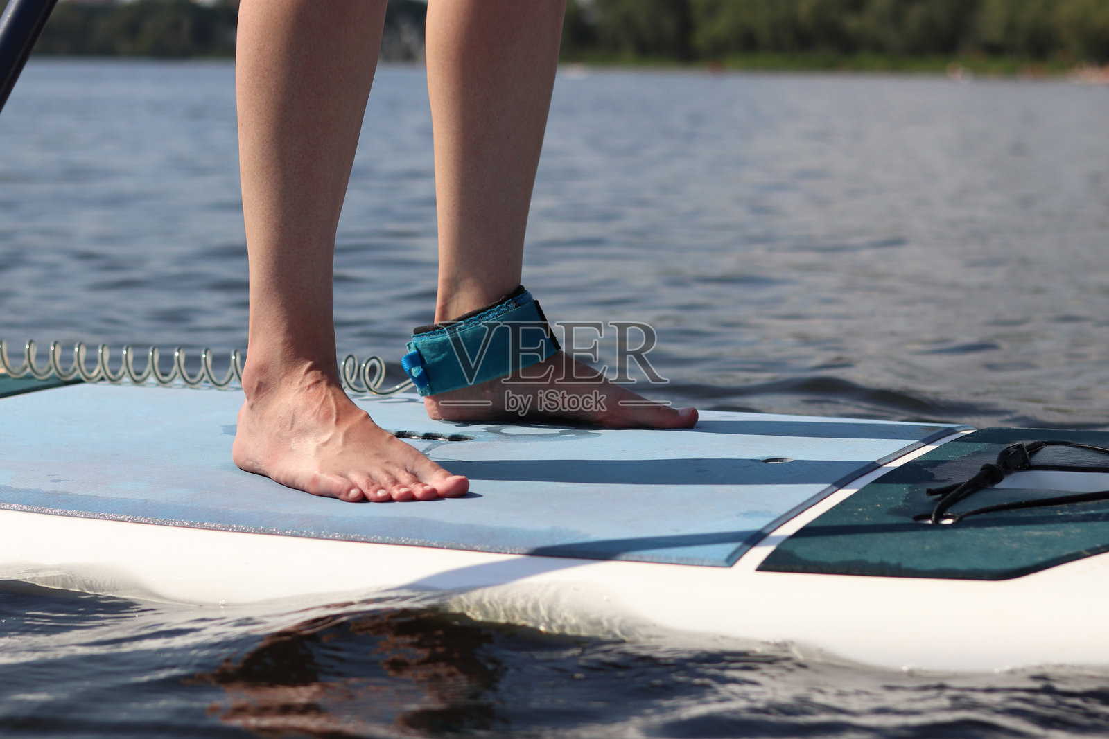 女性双腿特写，站在立式划水板上照片摄影图片