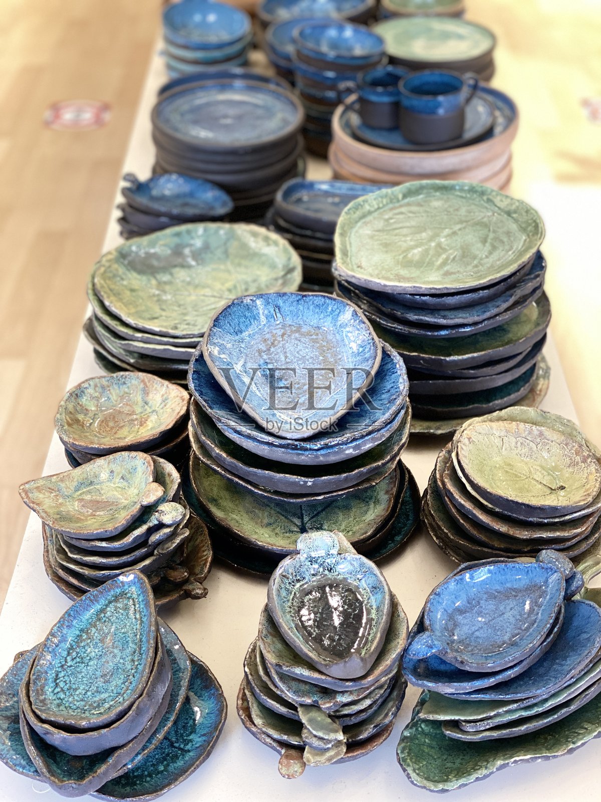 蓝绿色釉面陶瓷餐具堆叠在木质表面上照片摄影图片