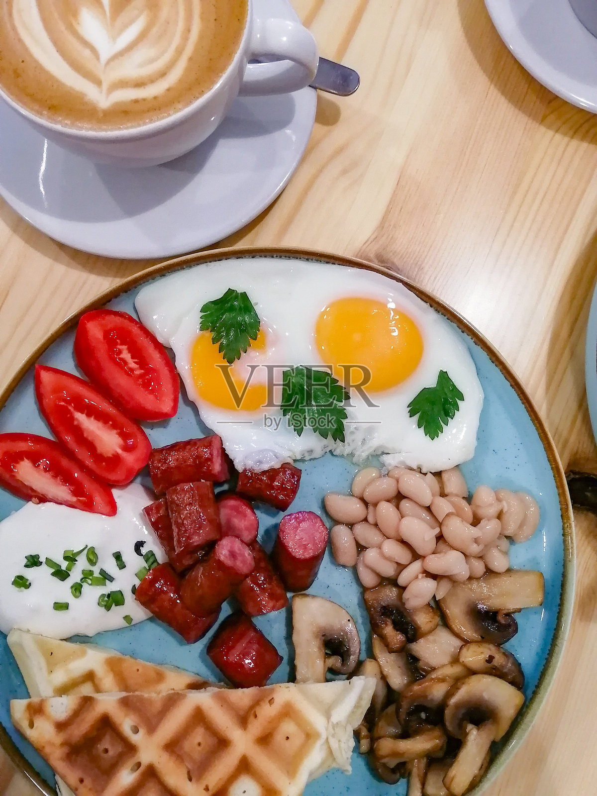 早餐包括煎蛋、香肠、豆类、蘑菇和番茄，搭配香气四溢的招牌咖啡。照片摄影图片