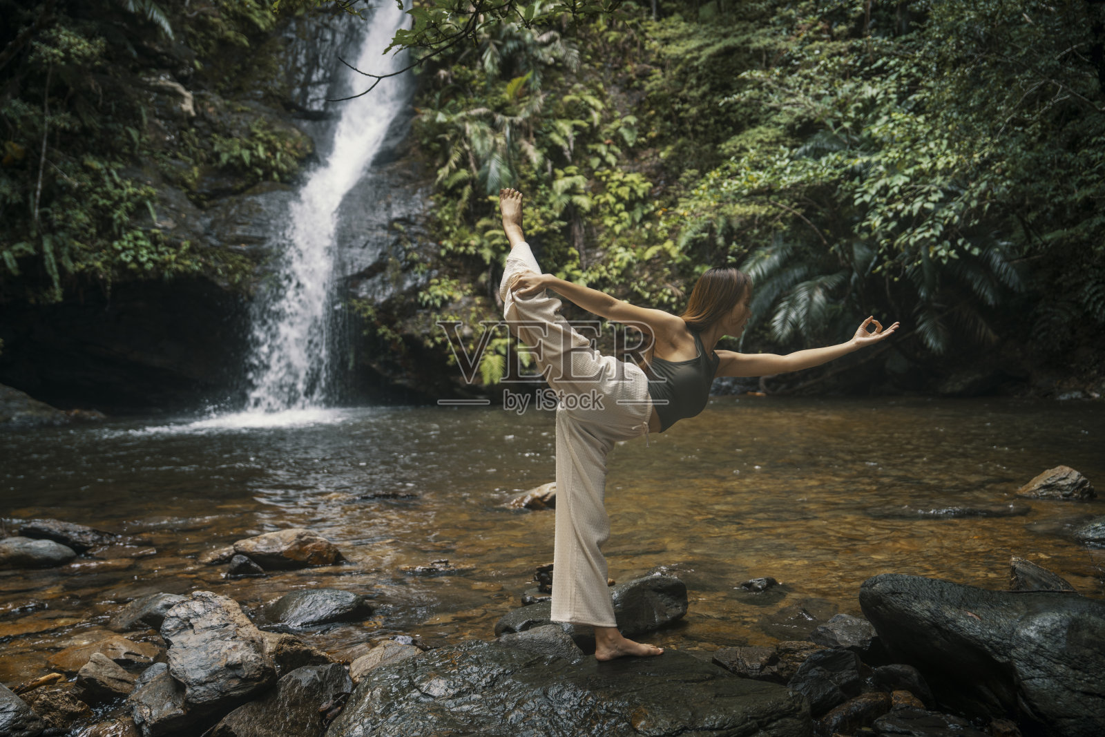 在瀑布前做瑜伽的成年女性照片摄影图片