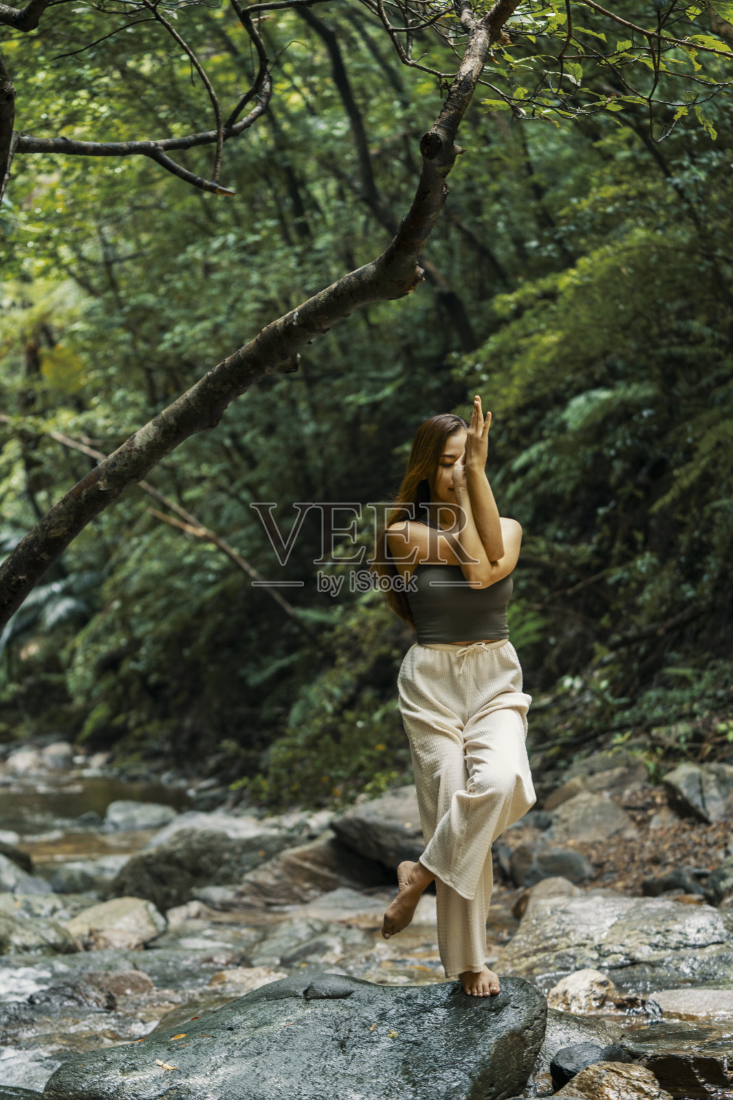 成年女性在丛林河流中做瑜伽照片摄影图片