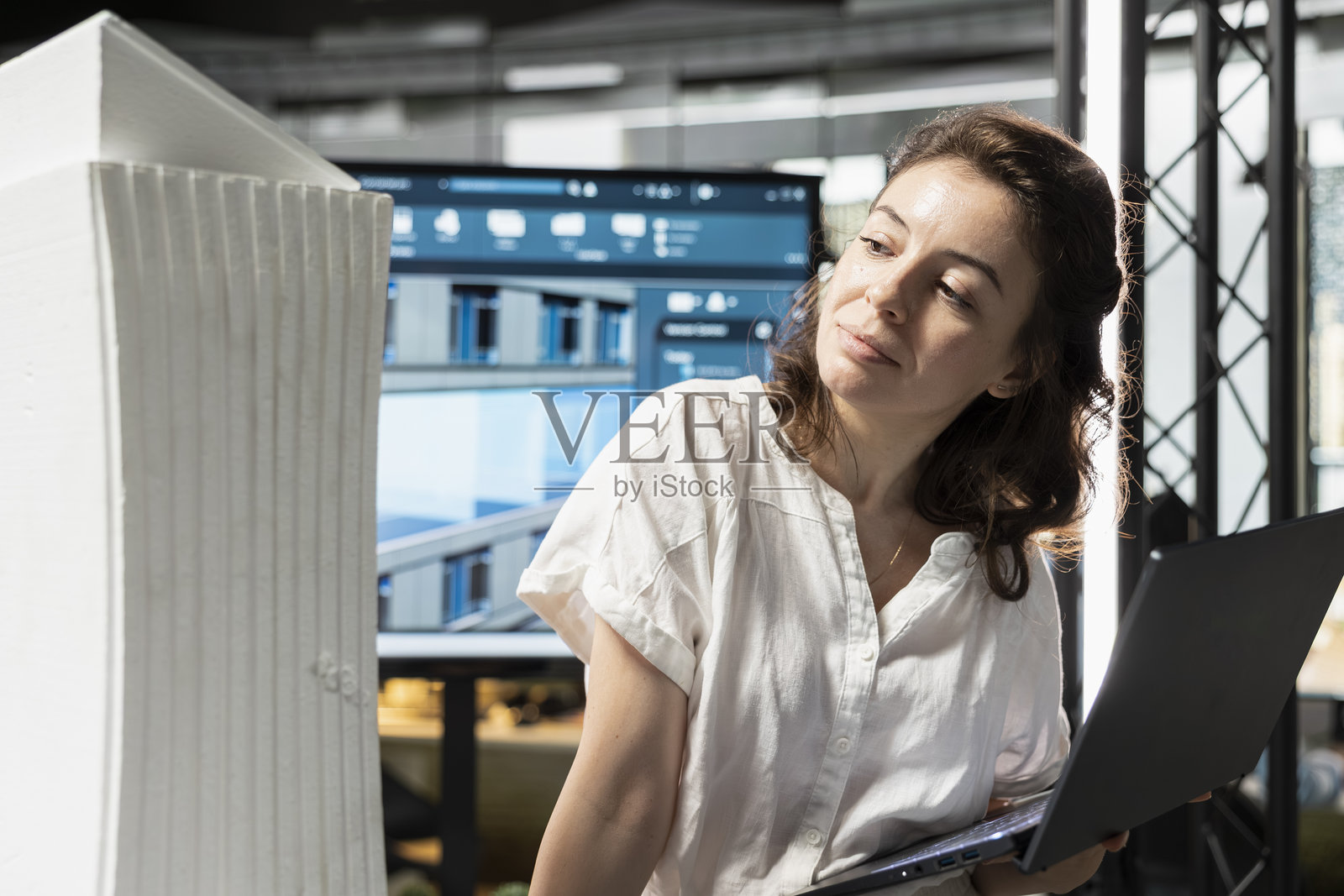 女性房地产专业人士正在用笔记本电脑审查3D建筑模型照片摄影图片