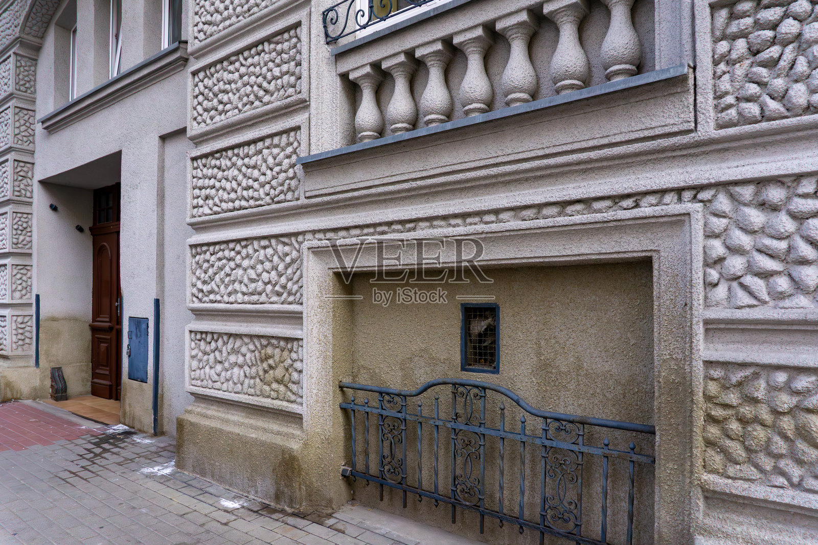 卡利什一栋公寓的外立面，装饰性灰泥、小地下窗户，以及人行道旁的锻铁保护格栅。照片摄影图片