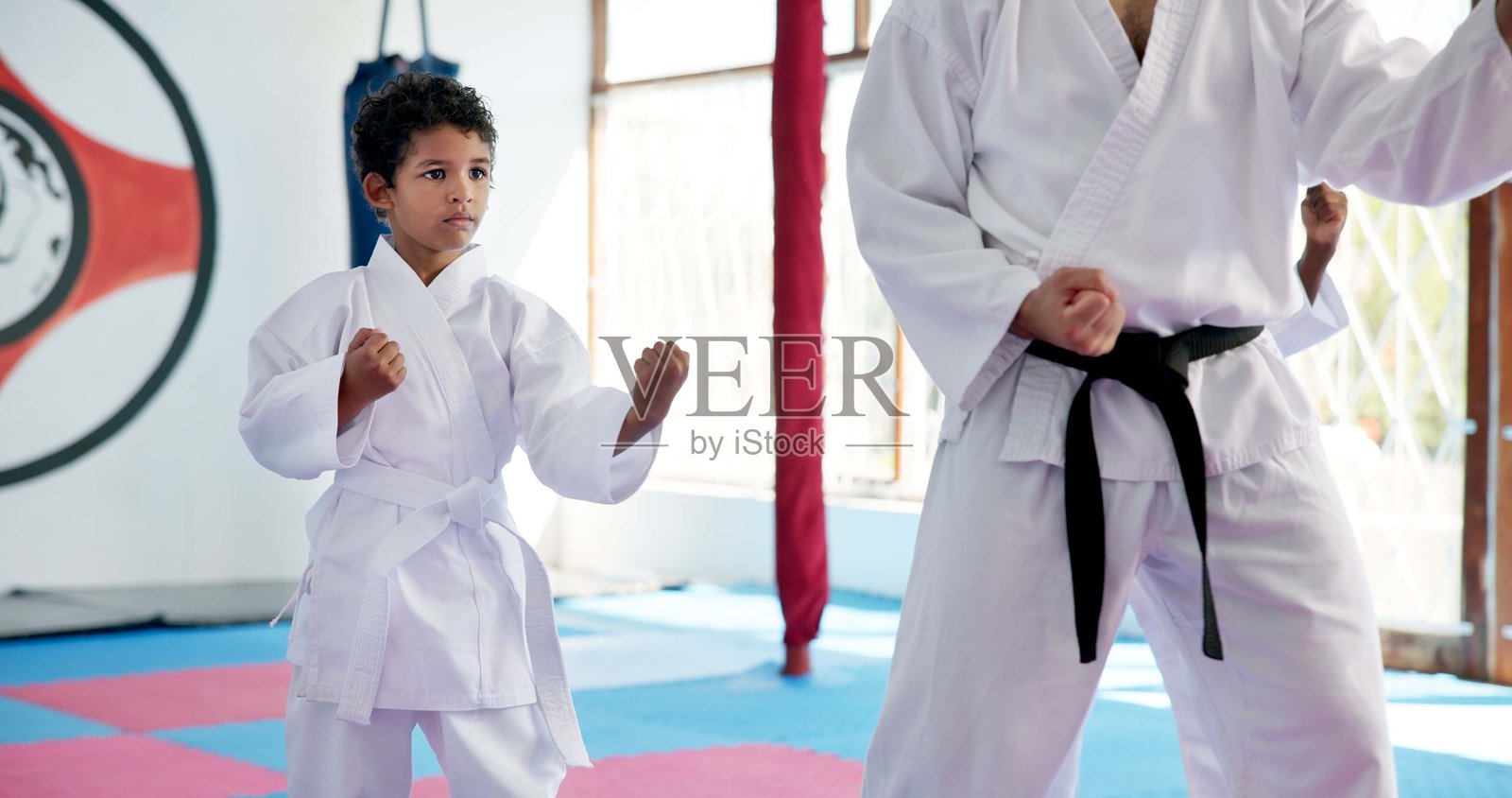 男孩、老师和学生在空手道课上，摆出自卫姿势或武术姿势，进行青少年战斗教育。跆拳道训练，教练与男孩在道场中指导。照片摄影图片