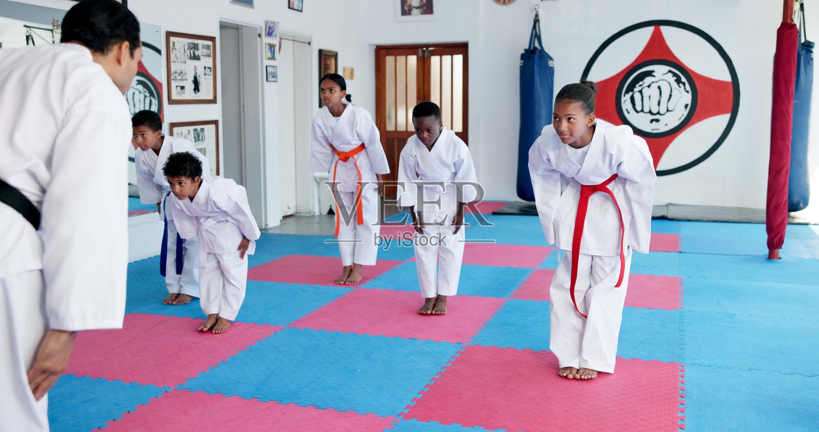 在道场中，孩子们向教练鞠躬以示尊重，学习自卫、传统或武术习俗。教练和学生们为战斗做好准备，培养纪律和跆拳道的健身或运动。照片摄影图片