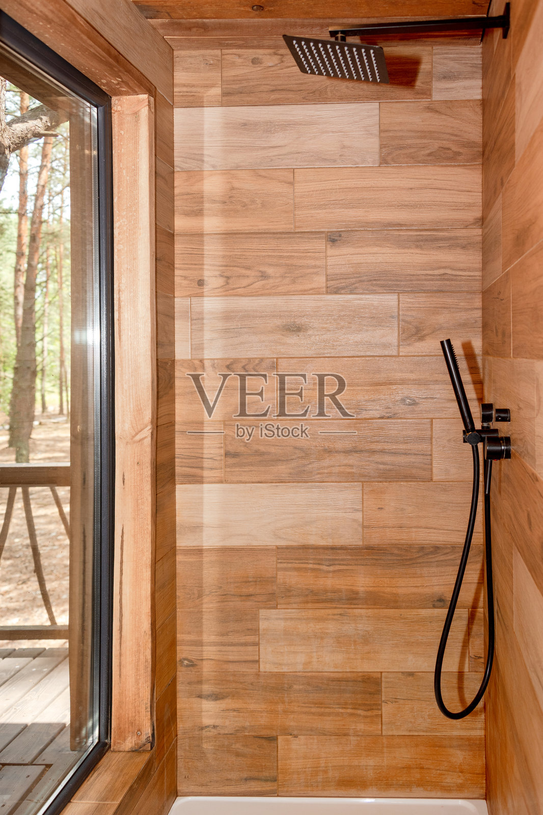一个舒适的木质淋浴间内部，展示了自然木板和一个俯瞰户外绿意的窗户。非常适合生态友好生活、自然度假和小屋美学的概念。照片摄影图片