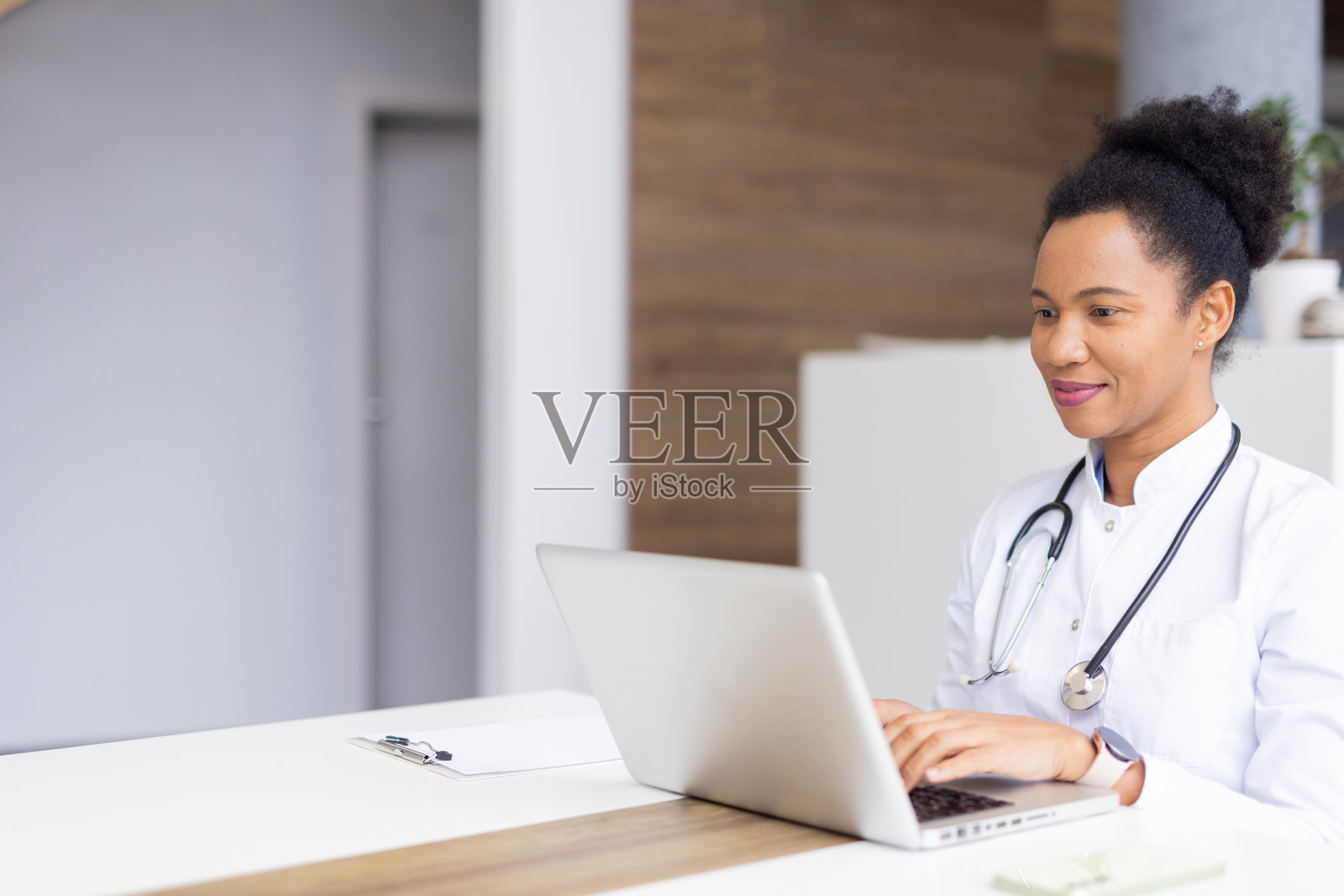 专业女性医生在时尚的医疗环境中查看患者数据，使用笔记本电脑工作照片摄影图片