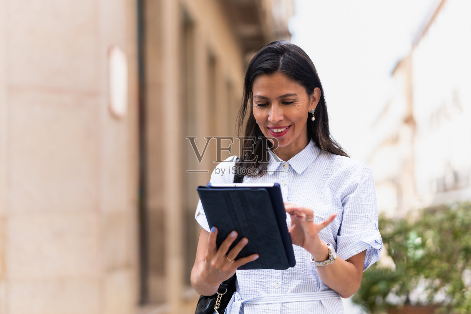 女商人在街上走路时使用数字平板电脑照片摄影图片