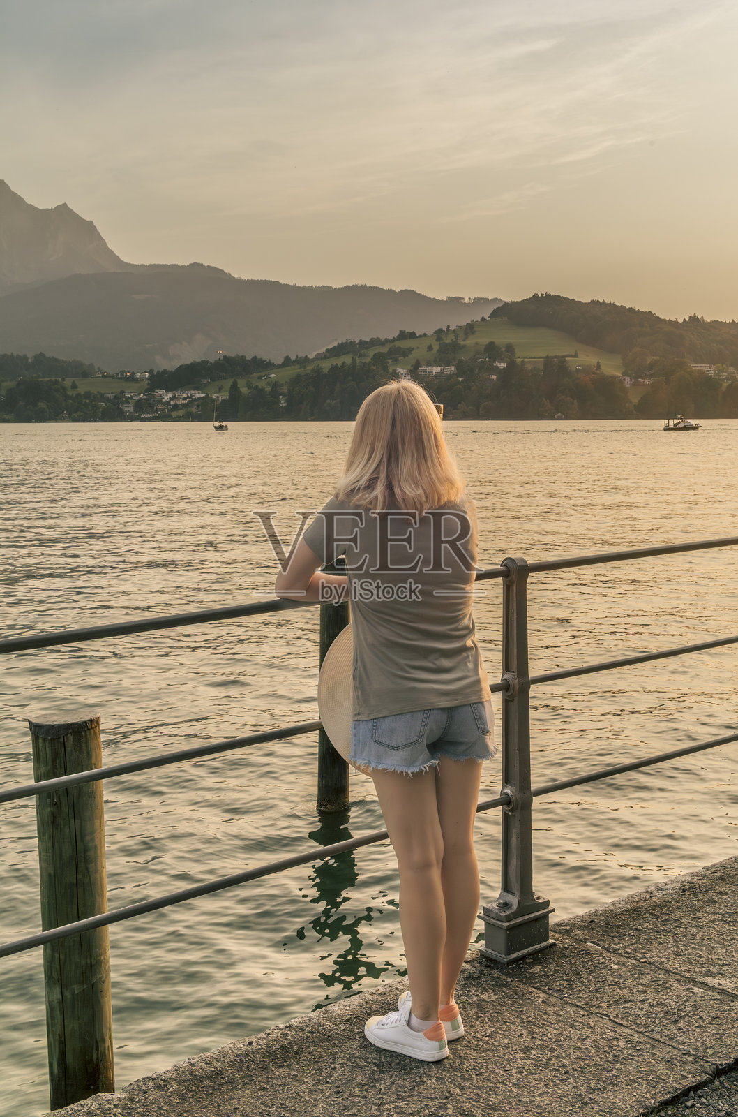 一位金发女郎在瑞士卢塞恩湖捕捉日落美景照片摄影图片