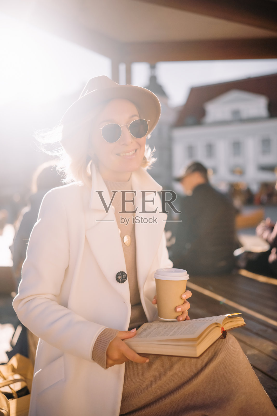 女人在阳光明媚的户外空间享受咖啡，同时阅读一本书照片摄影图片