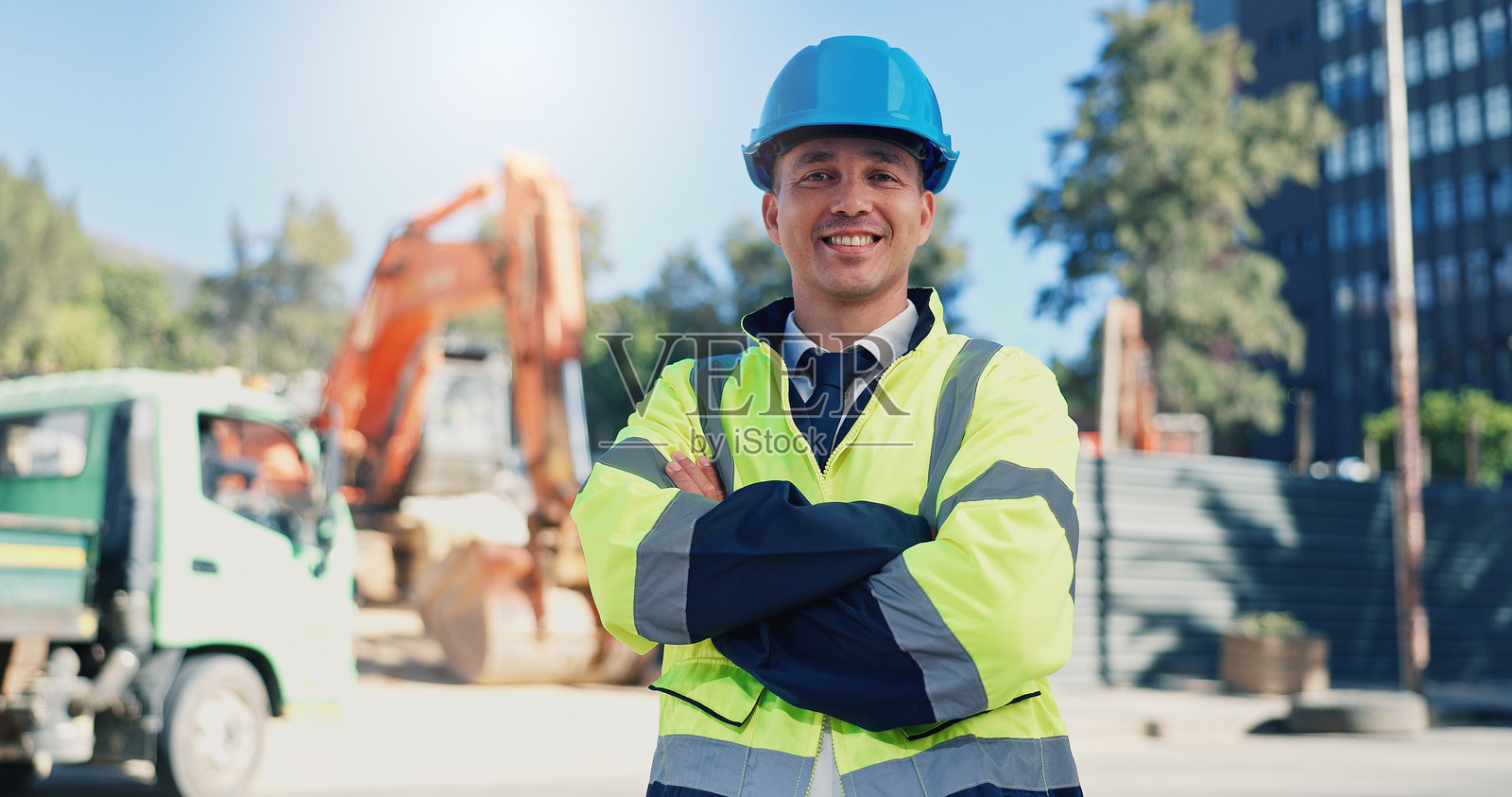 在建筑工地上，双臂交叉的男性建筑师，展现出对城市基础设施发展的自豪感。微笑的技术人员或工程师，佩戴安全帽，参与墨西哥的房地产扩展项目。照片摄影图片