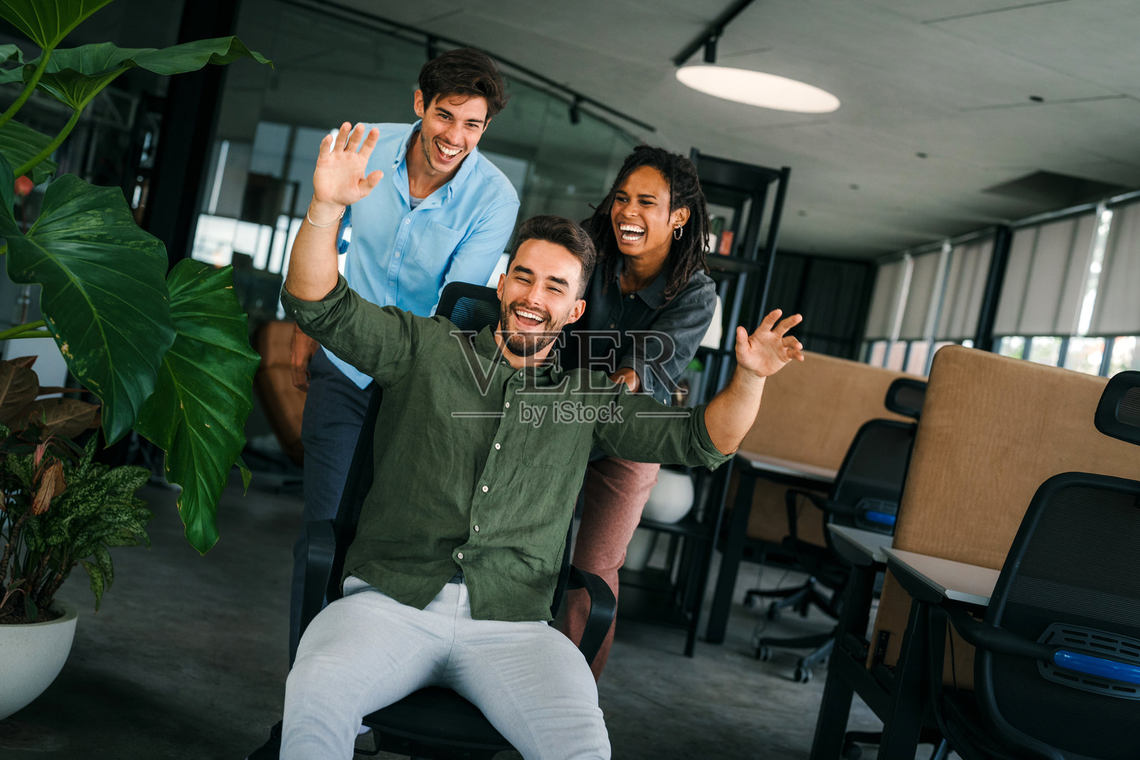 年轻多元化员工在现代创意办公室中欢欣鼓舞的肖像。团队建设照片摄影图片