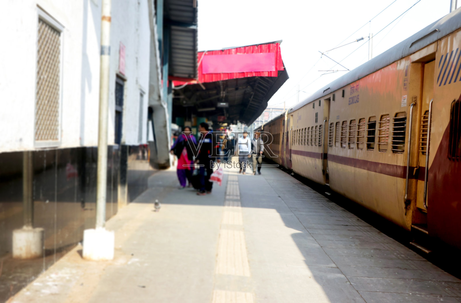 乘客在车站旁的铁路平台上走动，旁边停着一列火车照片摄影图片