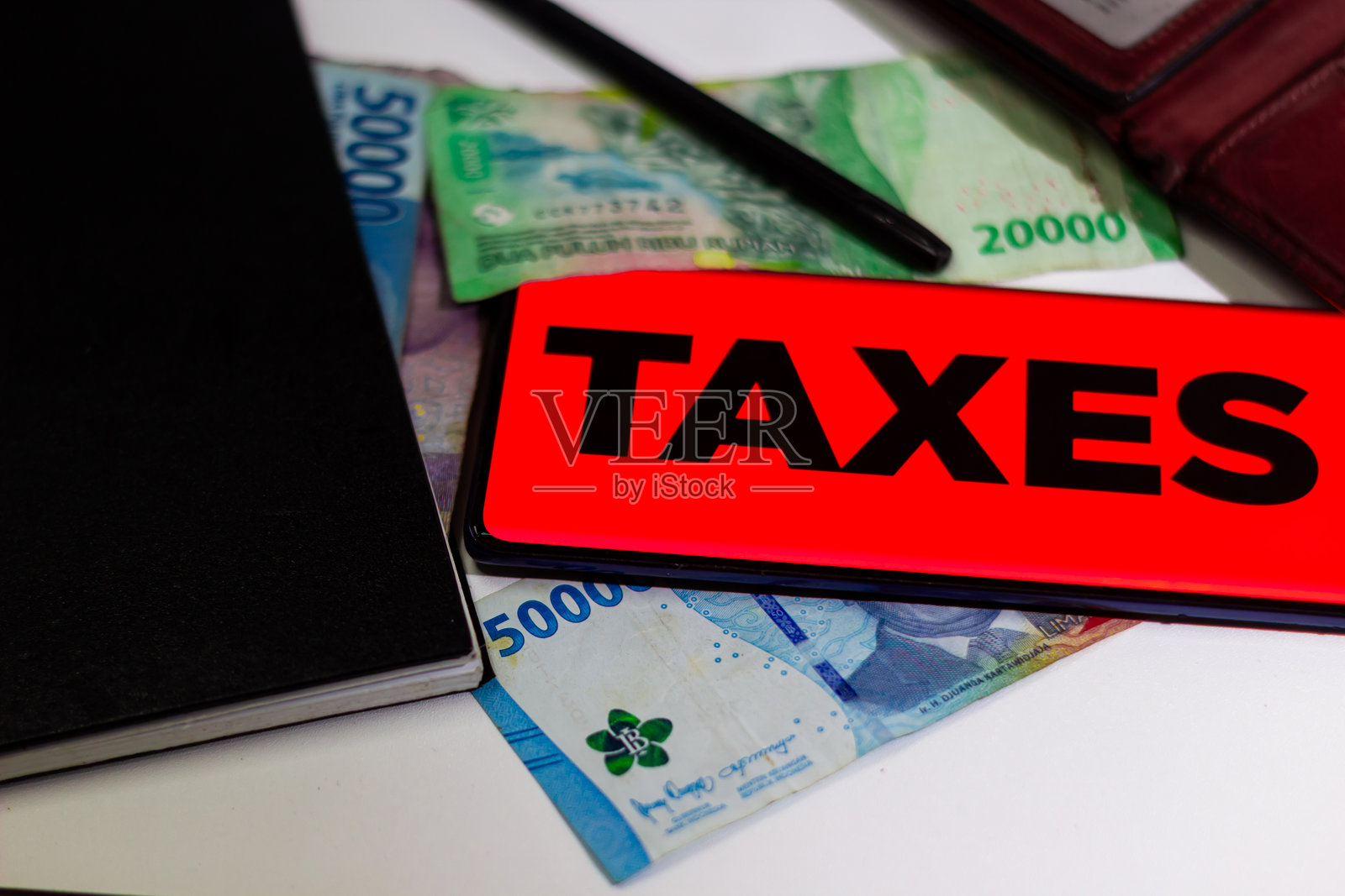 包含“税务”标志、外币、笔记本和钢笔的构图，营造出一个金融场景。照片摄影图片