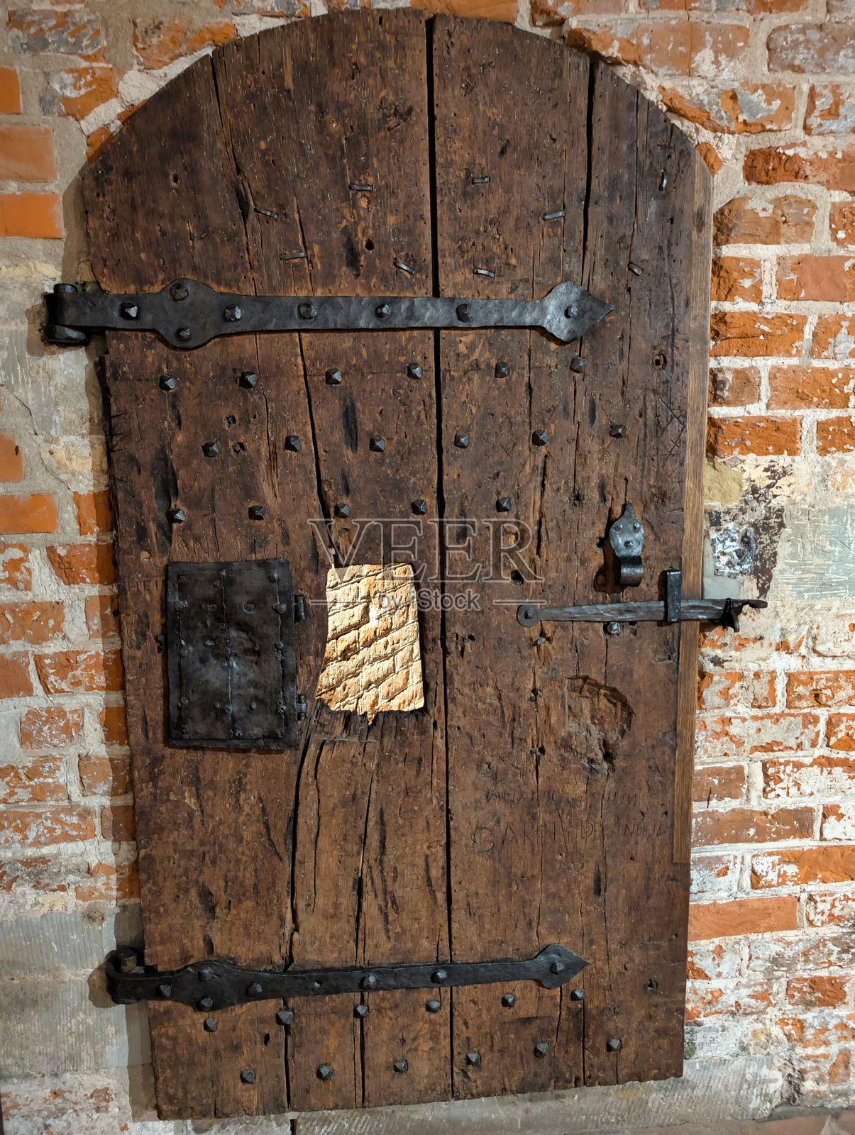 古老的木门配有铁制装饰，靠在历史建筑的砖墙上，夕阳西下。照片摄影图片