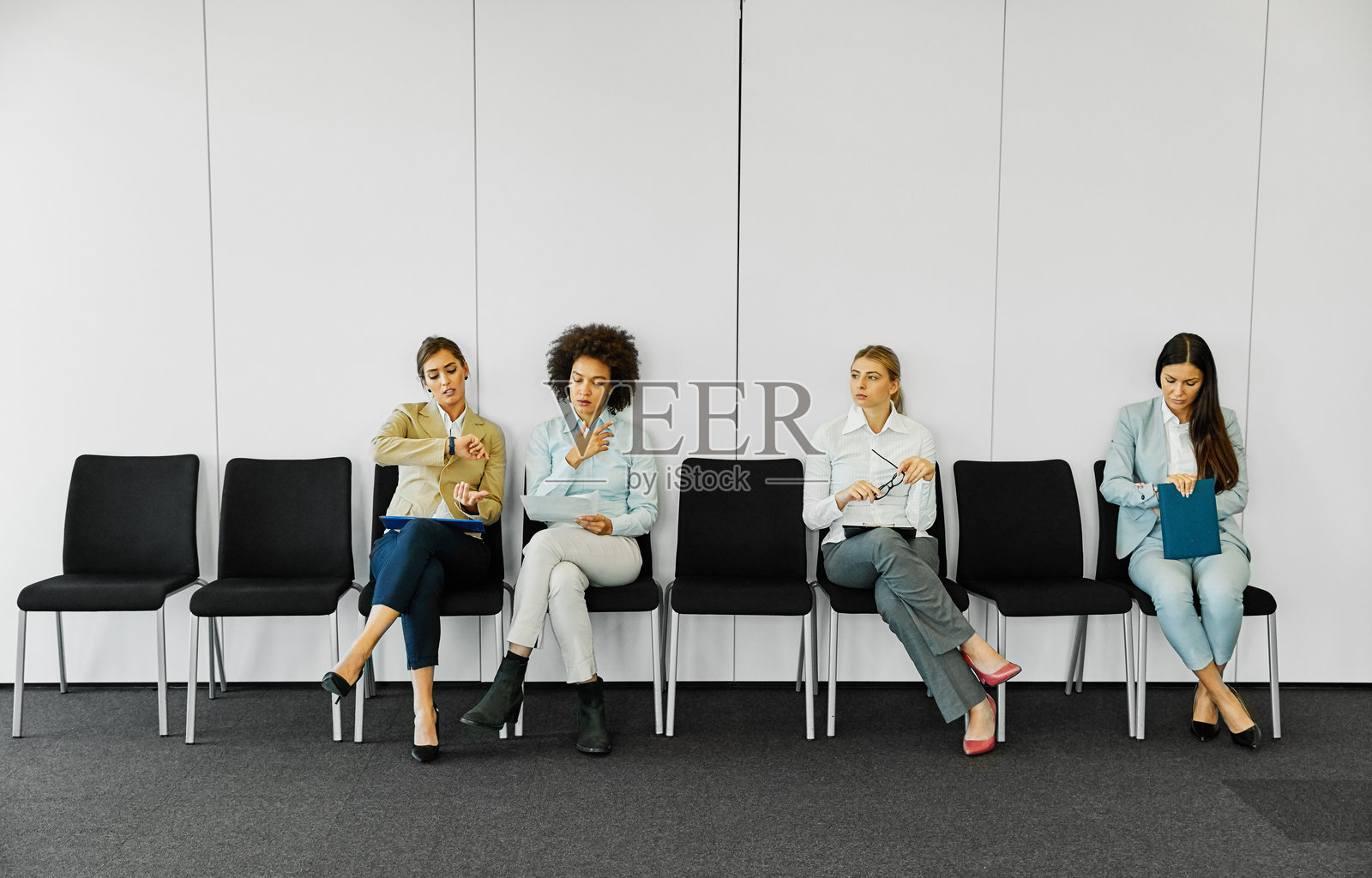 女性商务人士坐在椅子上等待面试，招聘办公室中的年轻候选人排队。照片摄影图片