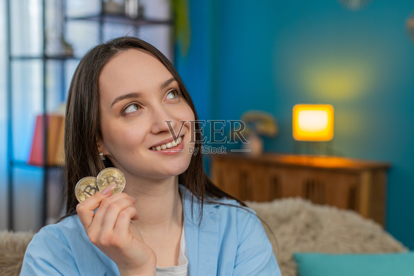 年轻女性兴奋地拿着加密货币，惊讶于加密货币的利润，正在分析投资。照片摄影图片
