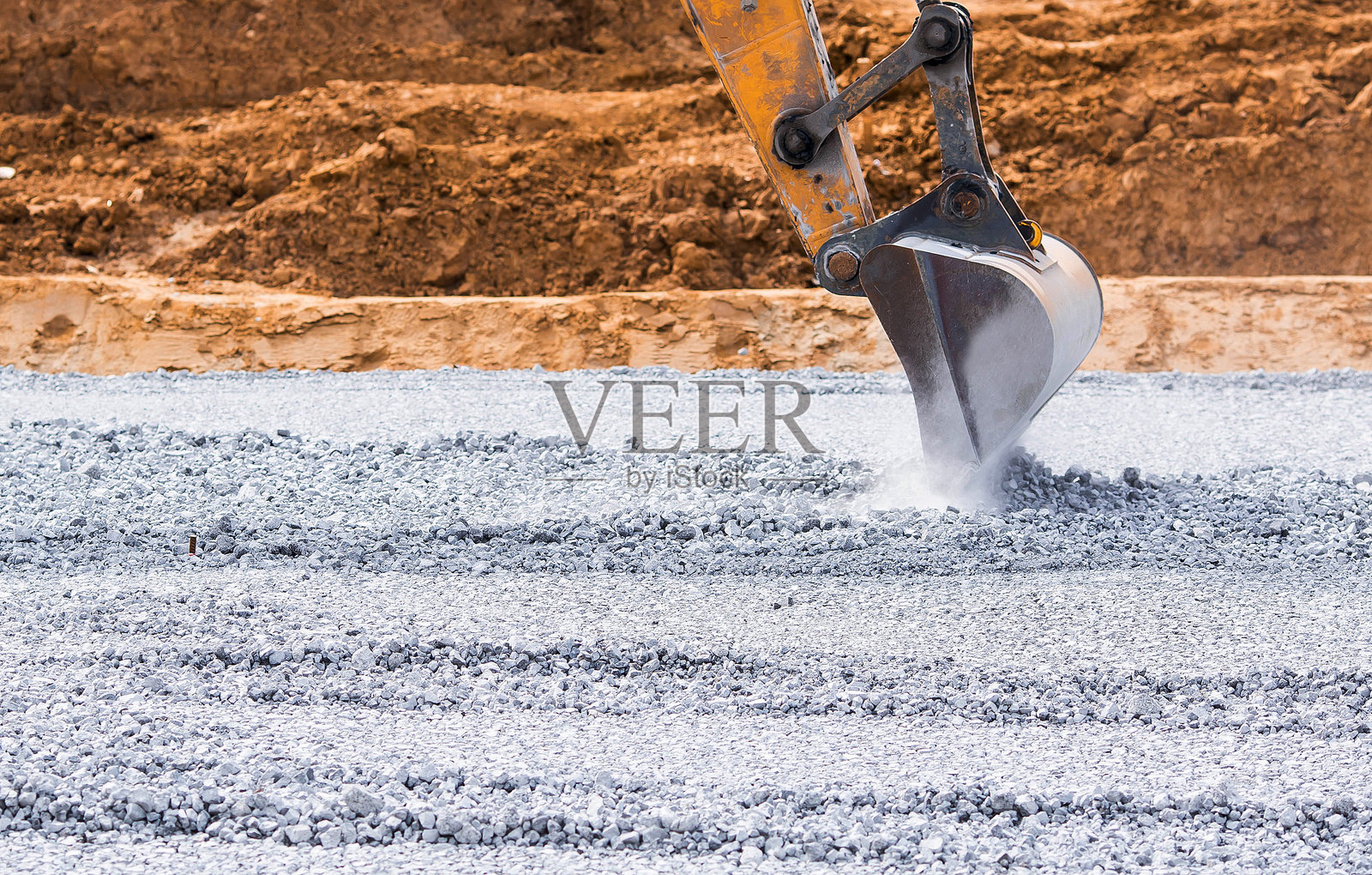 建筑工地上的挖掘机特写。挖掘机用铲斗撞击碎石进行施工。用于建筑和园林绿化的重型机械。照片摄影图片