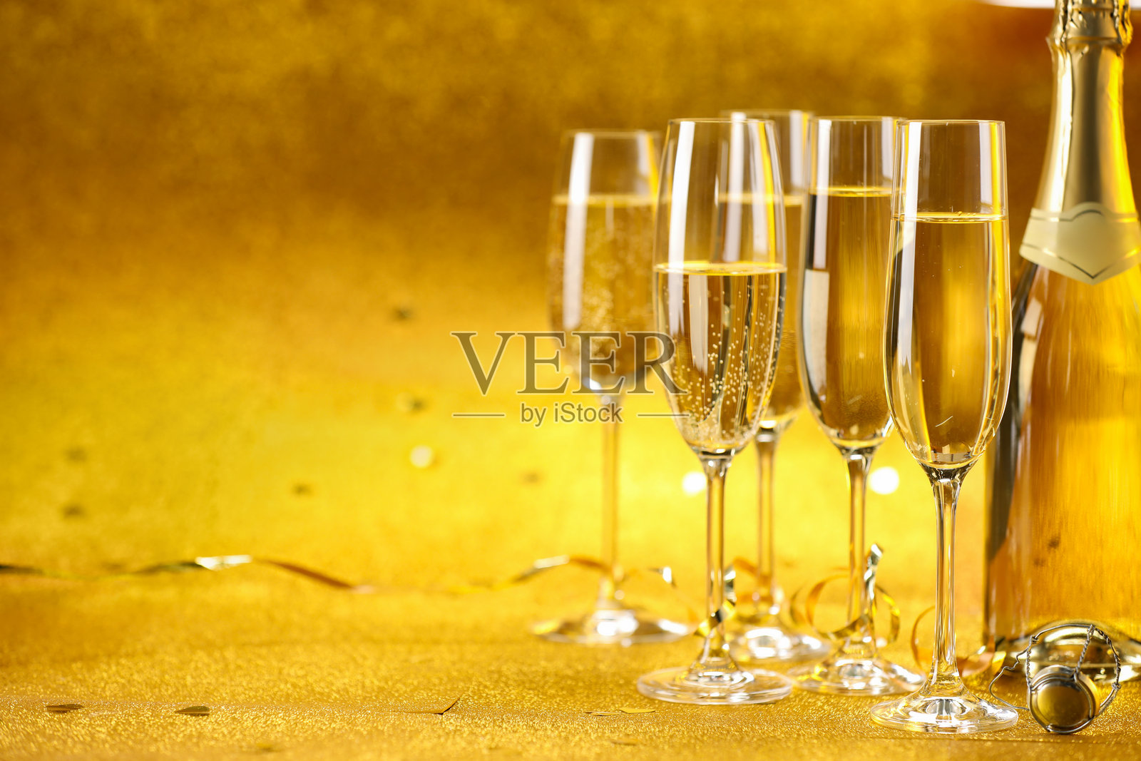 香槟、瓶子和金色背景上的彩带。留出文字空间照片摄影图片