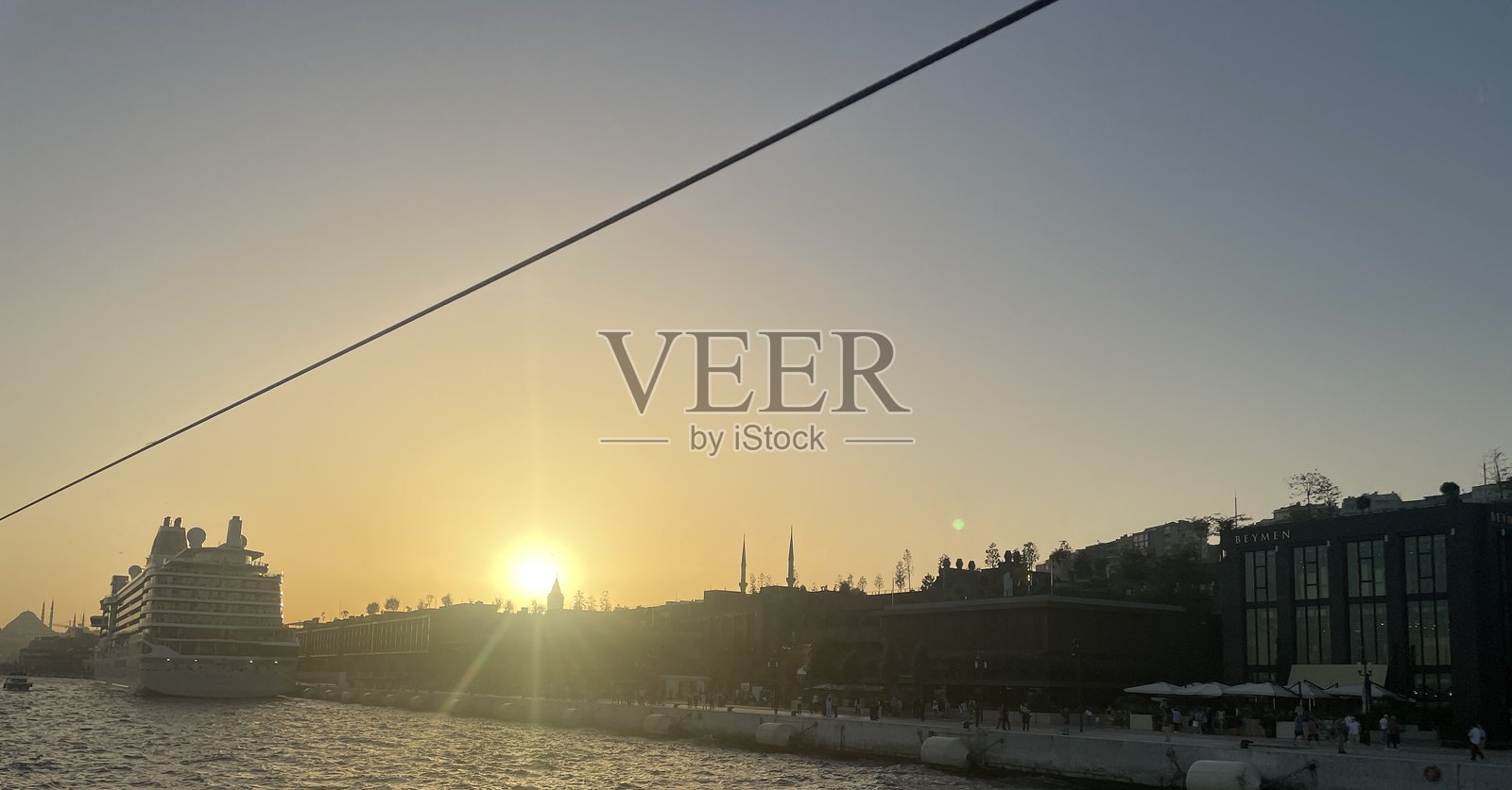 金色日落映照在加拉塔港，游轮与城市轮廓相映成趣。照片摄影图片