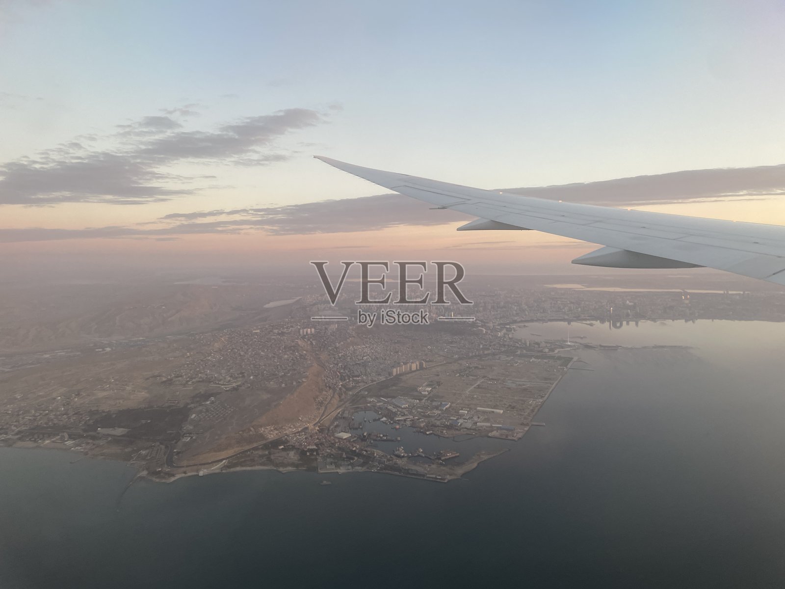 飞机上俯瞰海滨城市的日落景色。照片摄影图片