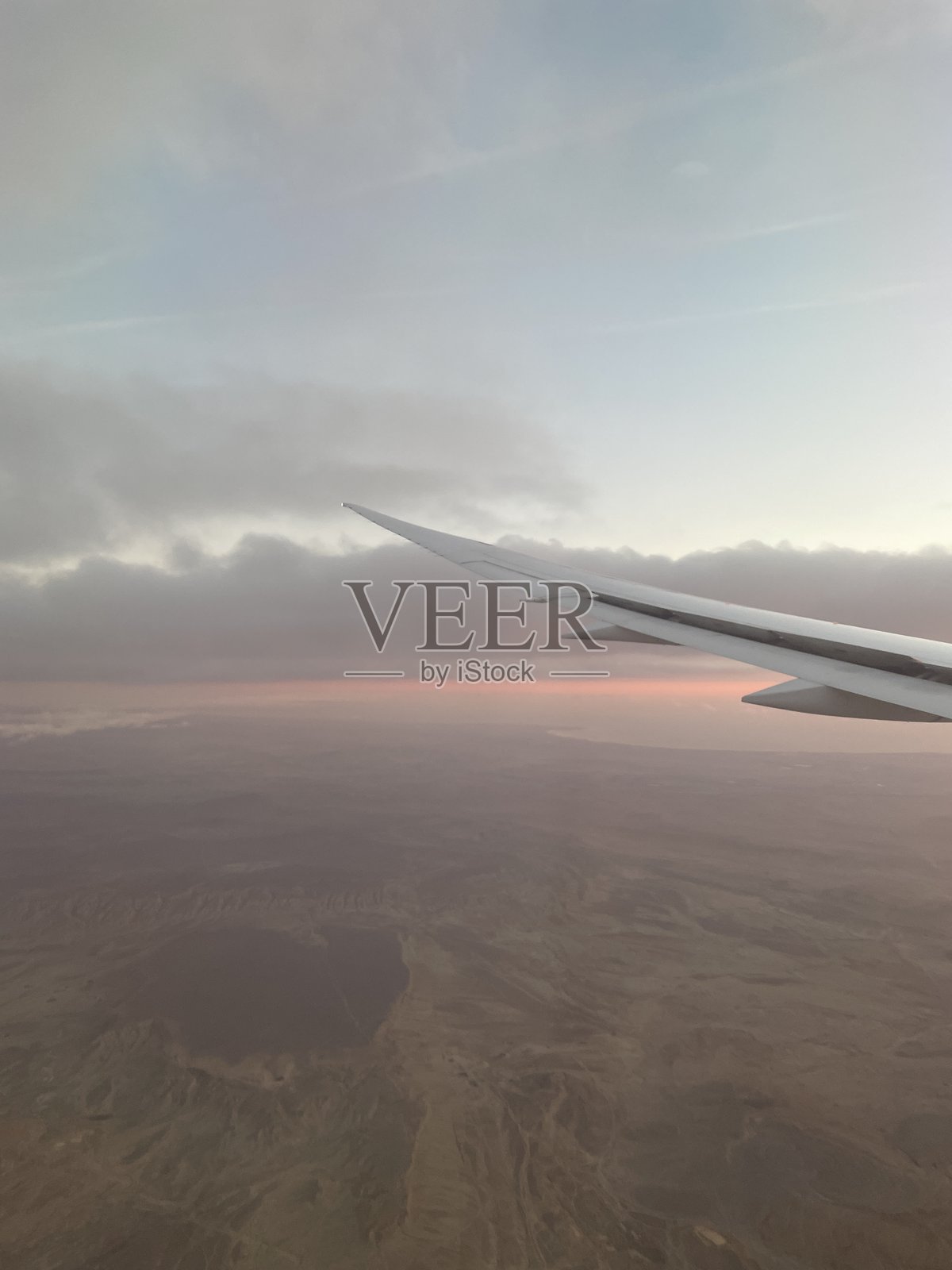 飞机机翼在日落/日出时的沙漠风景上方照片摄影图片