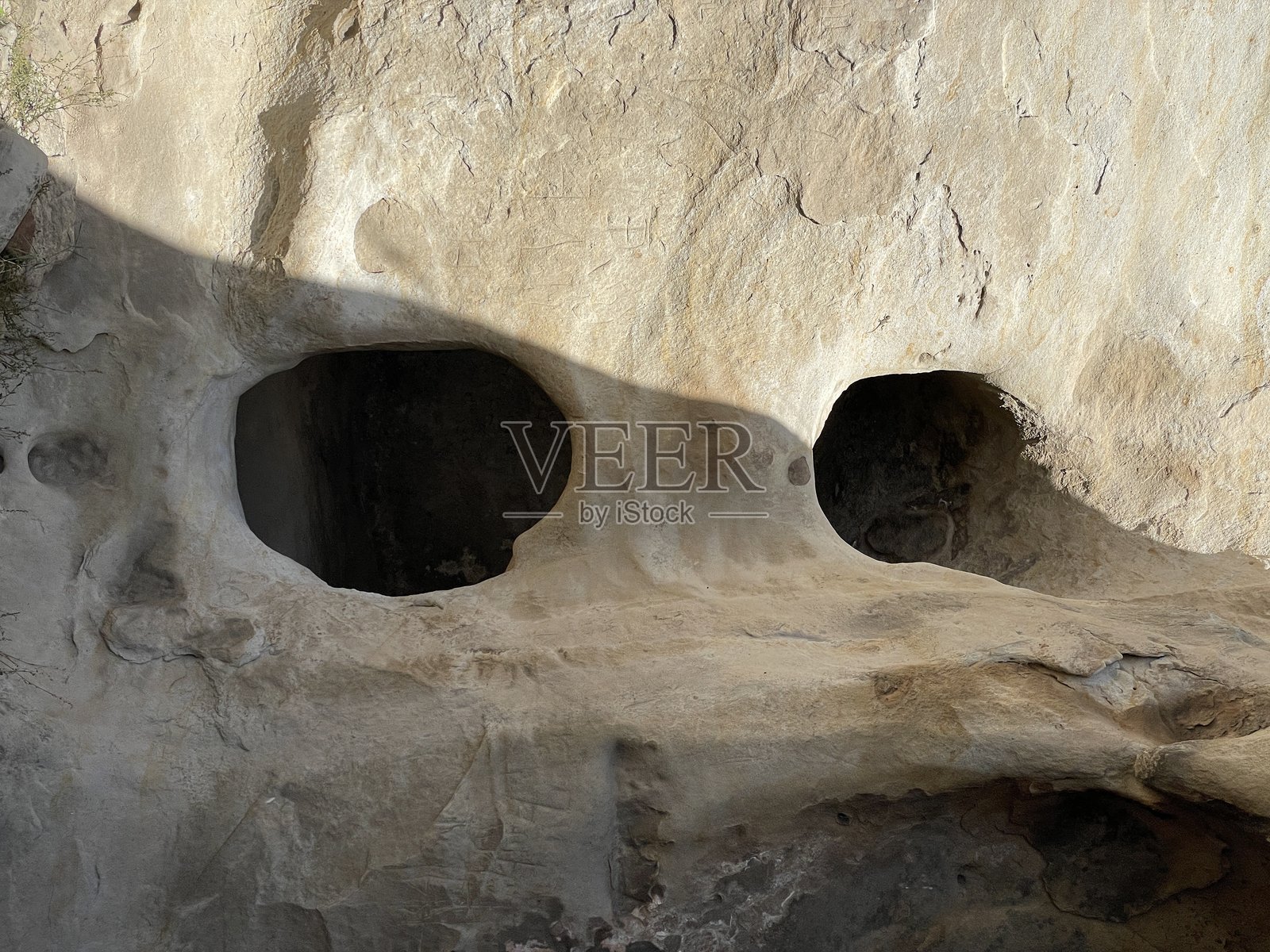 阳光照射下的岩石面，黑暗的洞穴入口和戏剧性的阴影。照片摄影图片