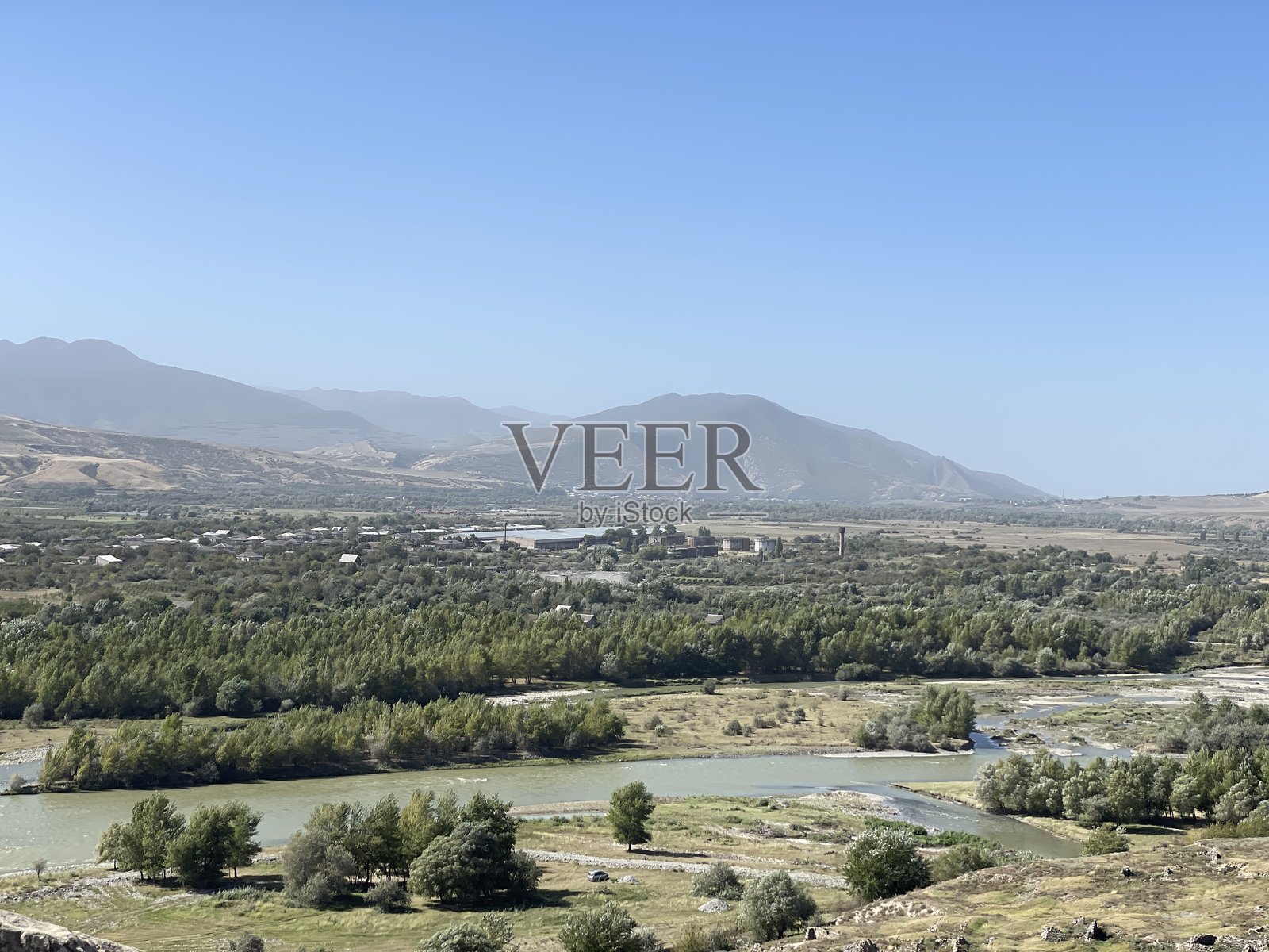 河谷与村庄；绿树；蓝天下的朦胧山脉。照片摄影图片