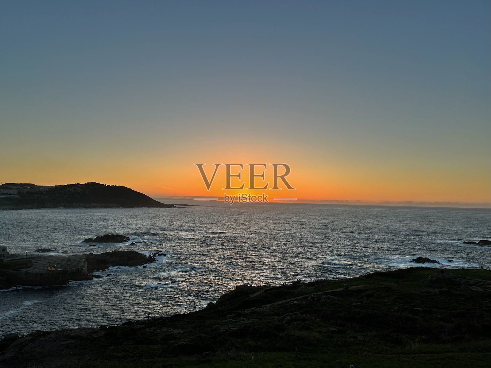 宁静海洋和海岸轮廓下的金色日落。照片摄影图片