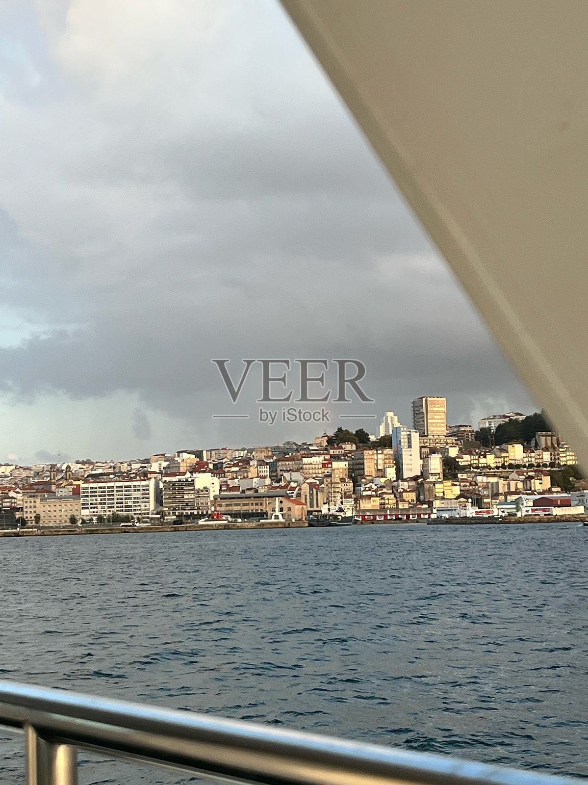 海上俯瞰丘陵沿海城市天际线上的淡淡彩虹。照片摄影图片