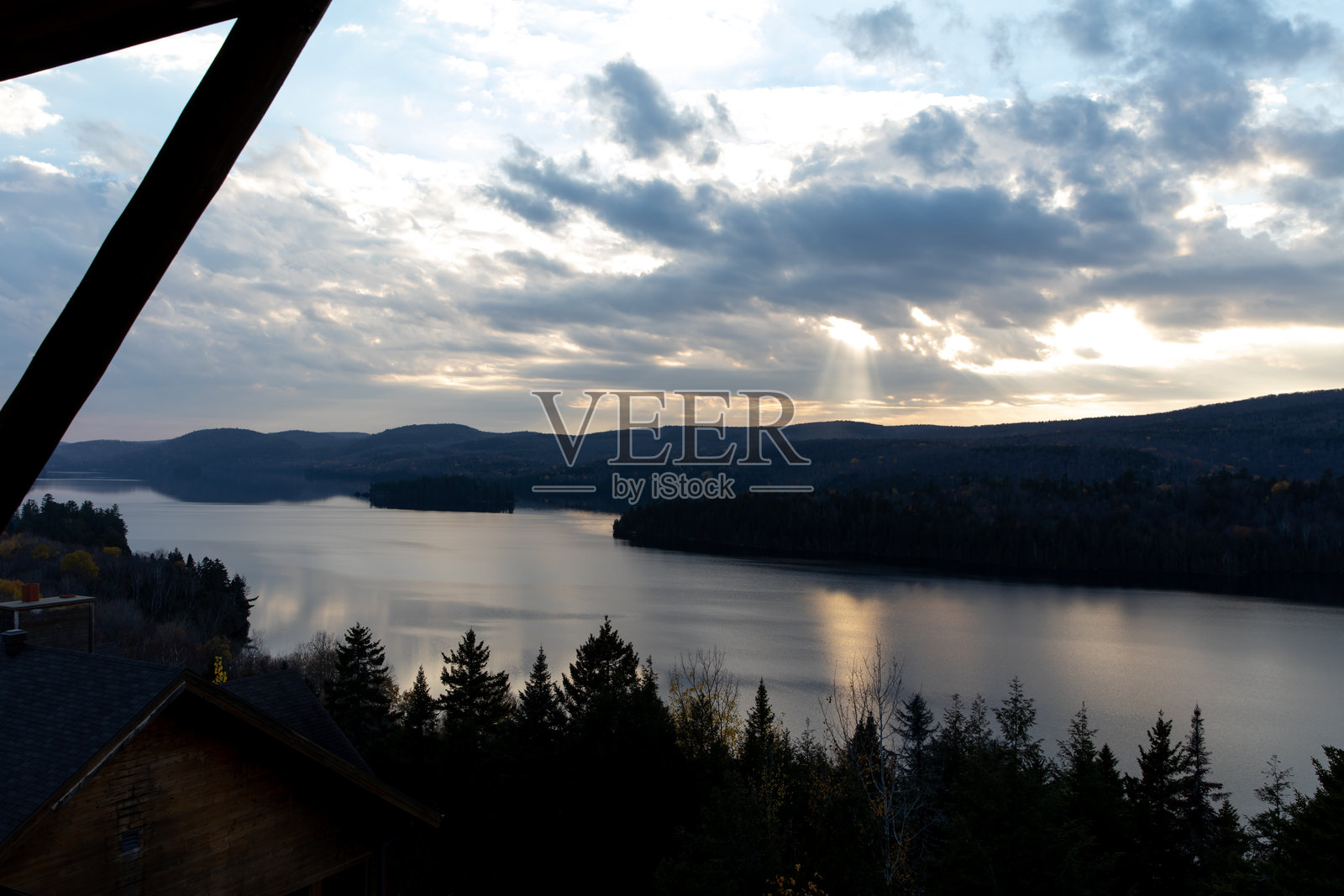 阳光照耀的云朵与森林环绕的湖景照片摄影图片