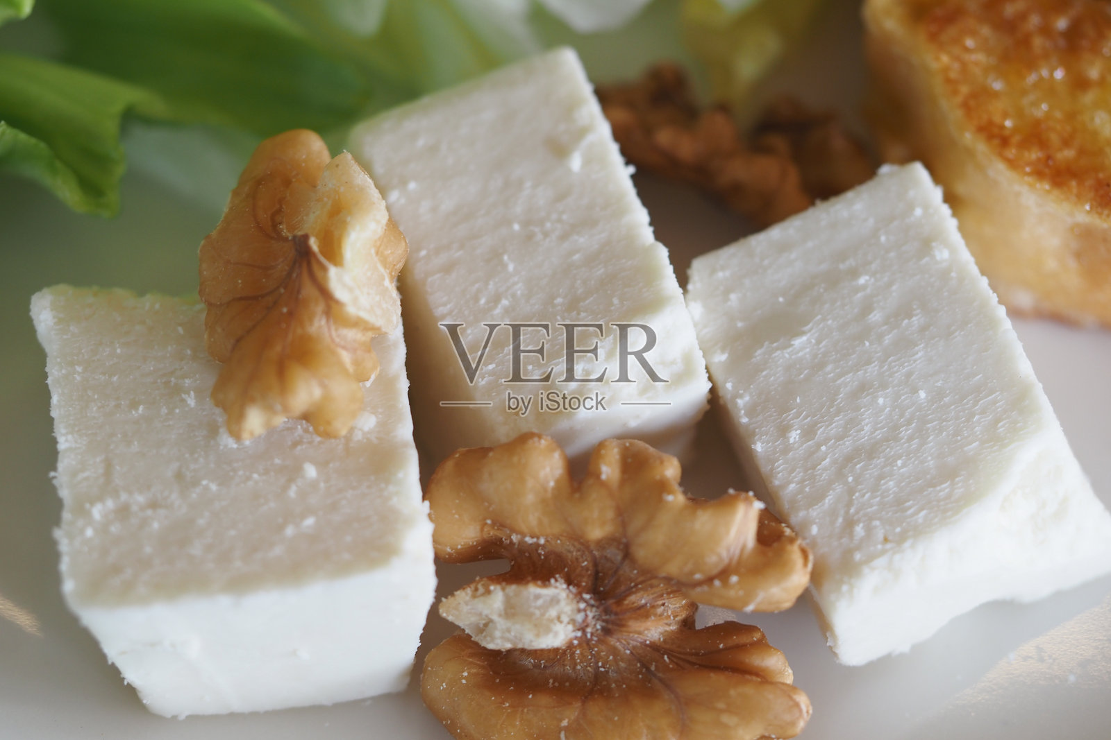 软奶酪和核桃搭配新鲜绿叶菜盛在盘子里照片摄影图片