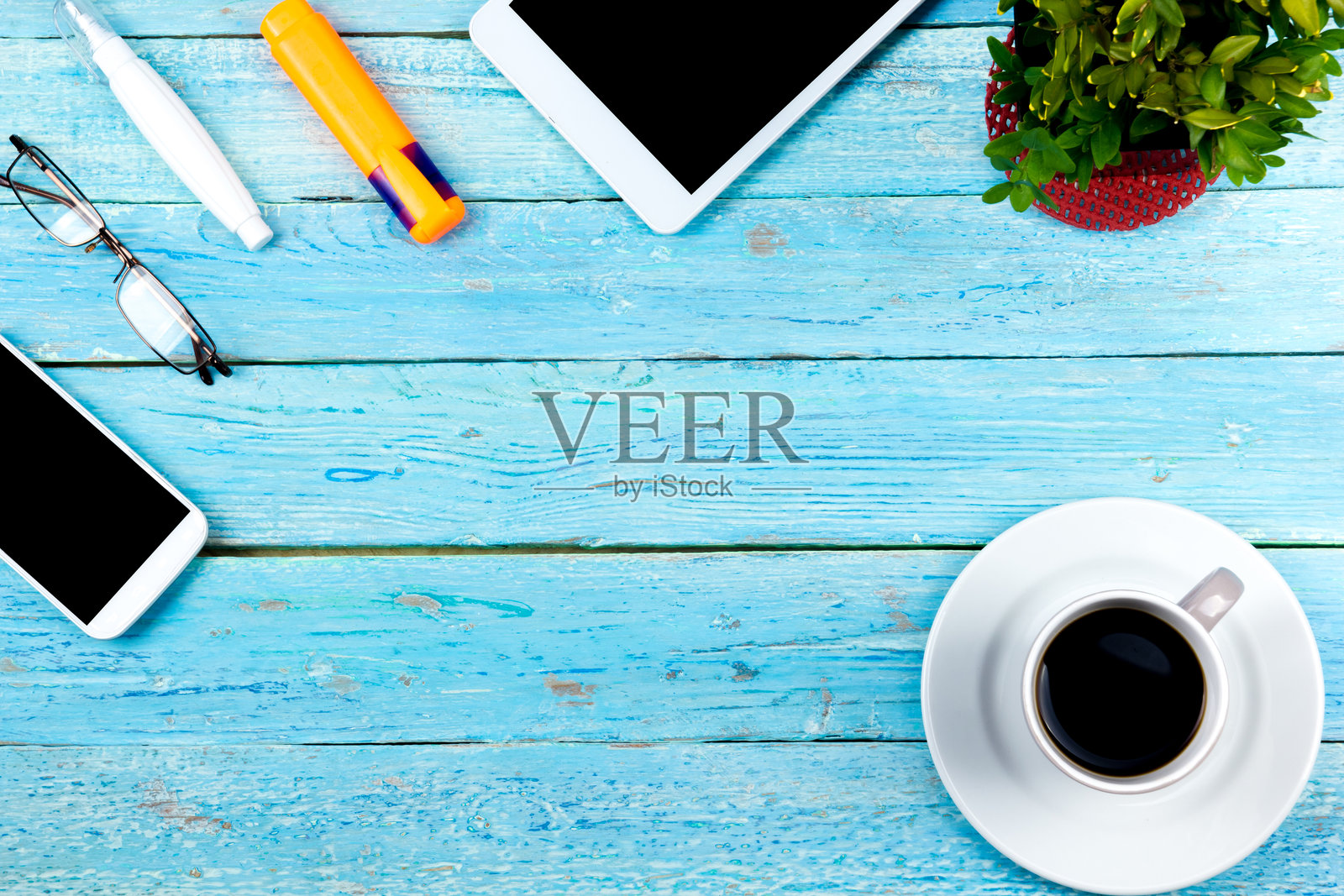 蓝色的办公桌子上有电脑，钢笔和一杯咖啡，很多东西。带复制空间的俯视图。照片摄影图片