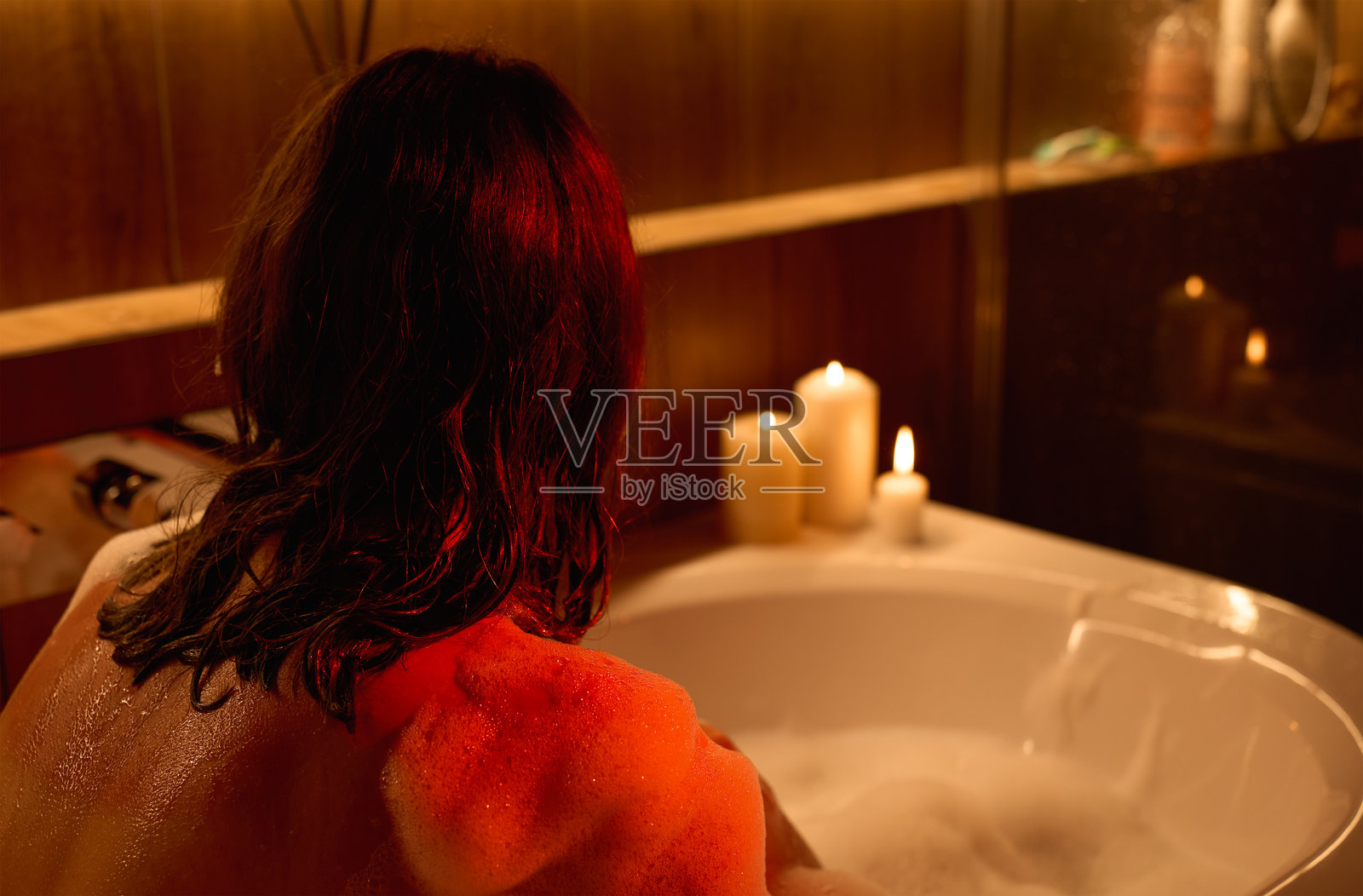 女人在泡泡浴缸中放松，周围点着蜡烛照片摄影图片