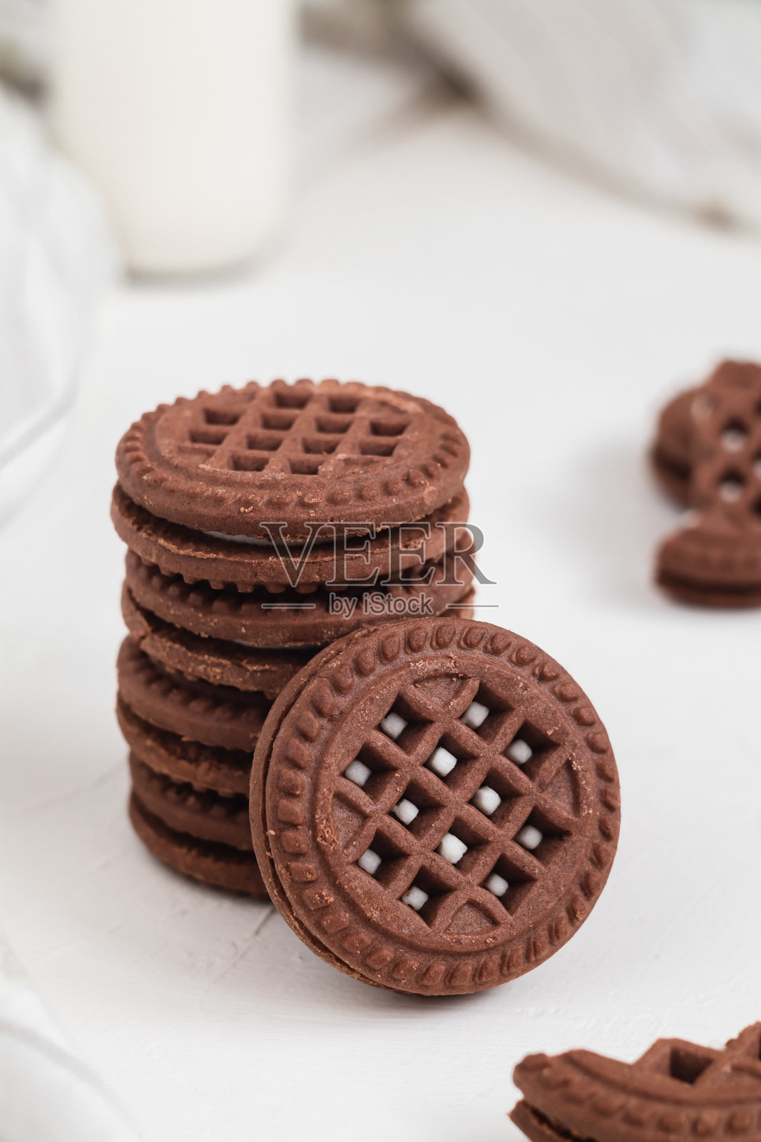 Round chocolate sandwich cookies close up with cream fiiling on a white table.照片摄影图片